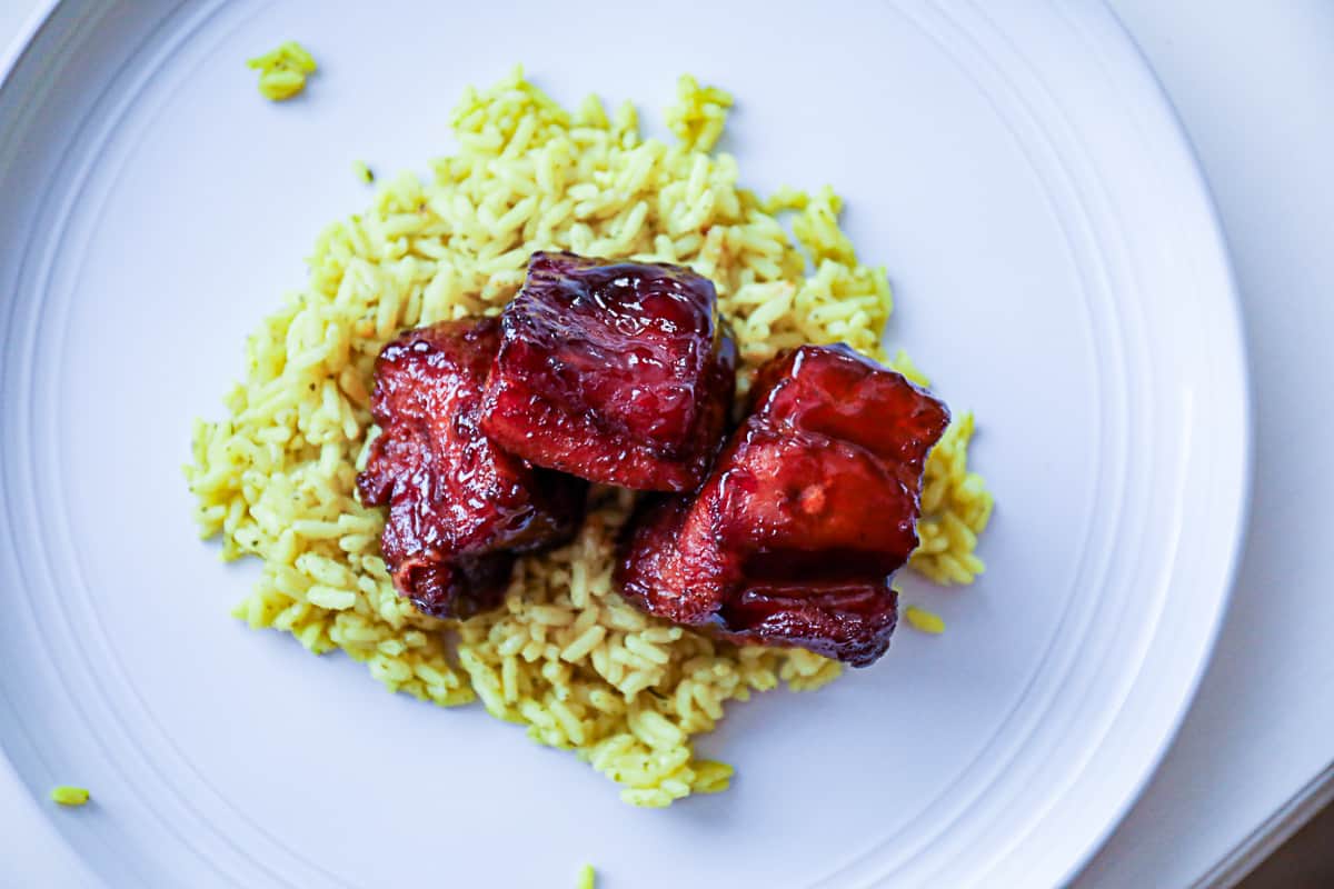 Serving BBQ smoked pork belly burnt ends cubed over rice plate