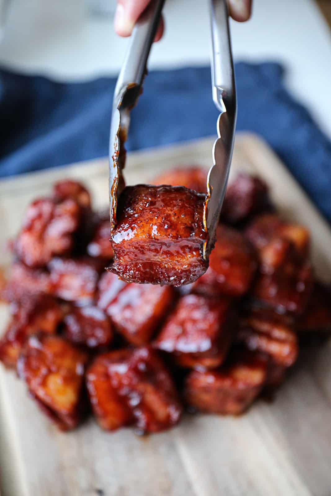 Tongs Holding Smoked Pork Belly Burnt Ends