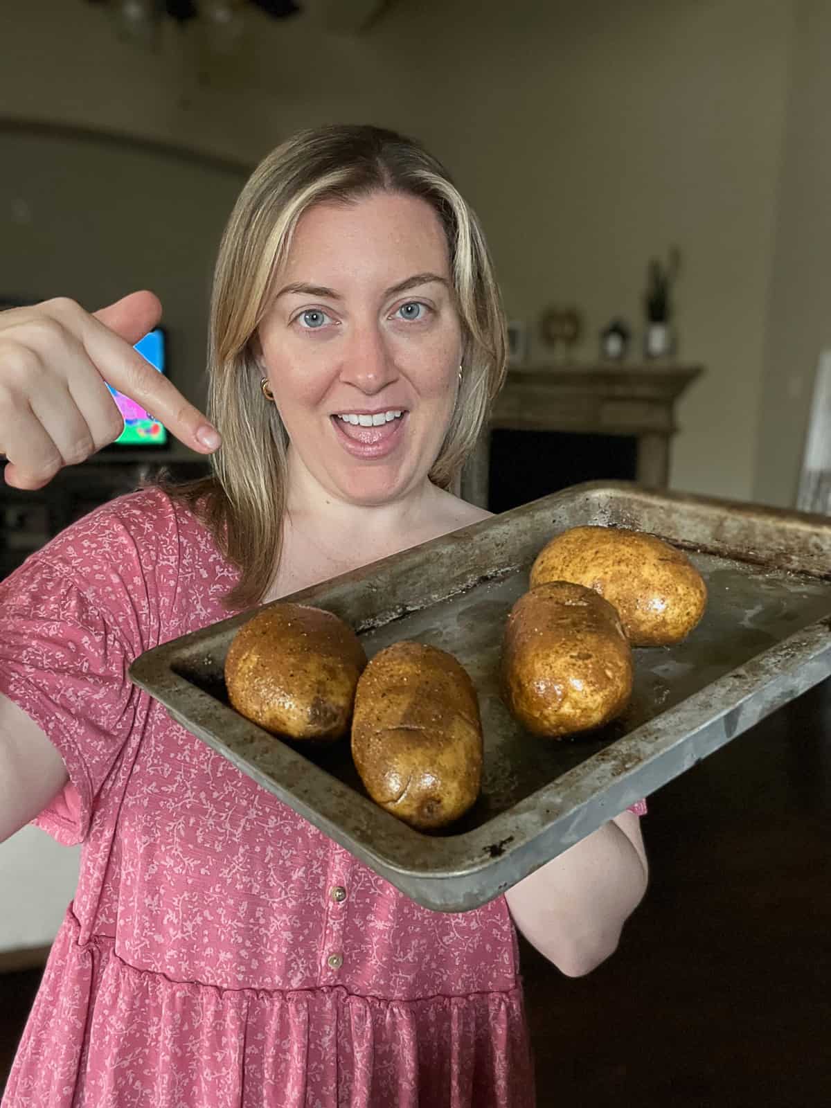 Food blogger holding russet baked potatoes seasoned for smoking on the Traeger pellet grill