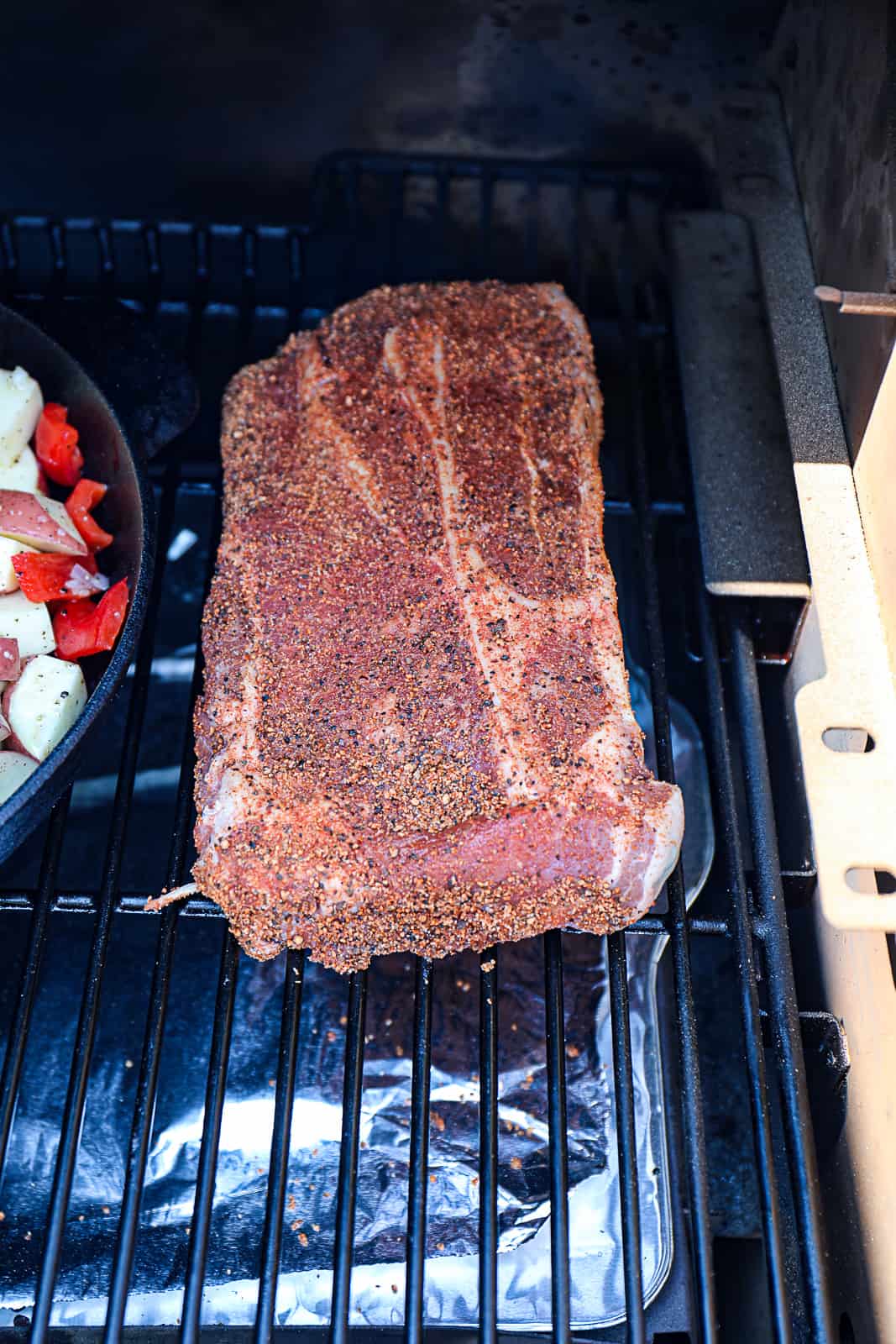 Seasoned 7 Bone In Chuck Roast Smoking on the Traeger pellet grill with potatoes