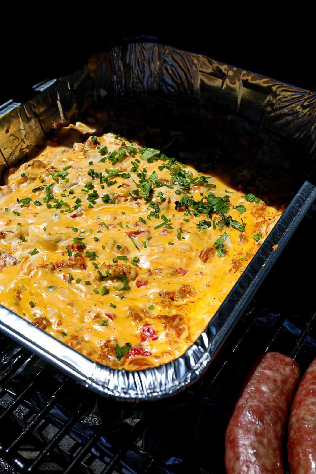Smoked Queso Made With Velveeta and Chorizo in an Aluminum Pan on the Traeger Pellet Grill with sausage