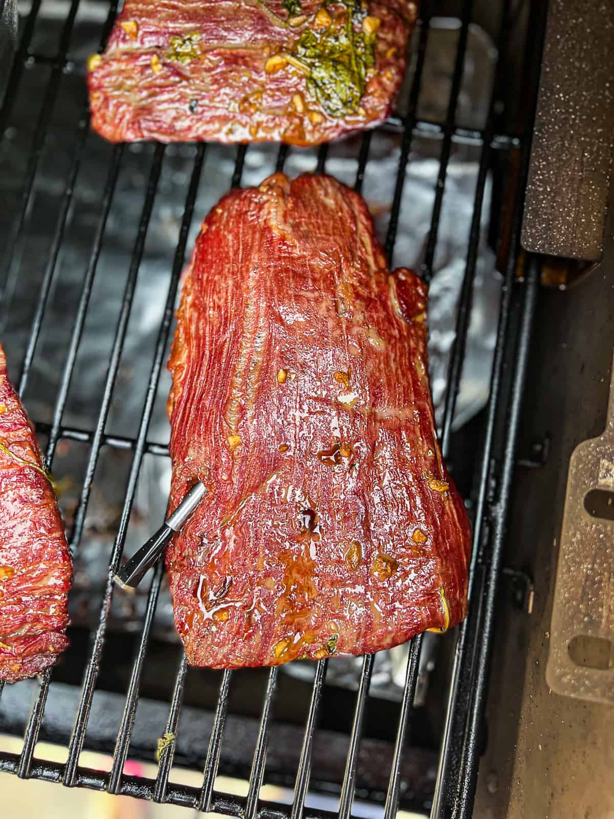 Smoking Traeger Flank Steak with Meater Thermometer inserted on the grill grates