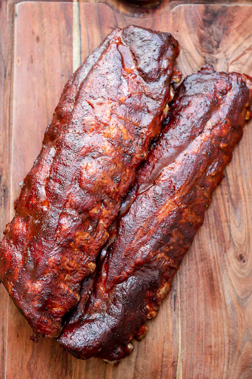 Treager Smoked 321 Ribs with BBQ sauce on a cutting board
