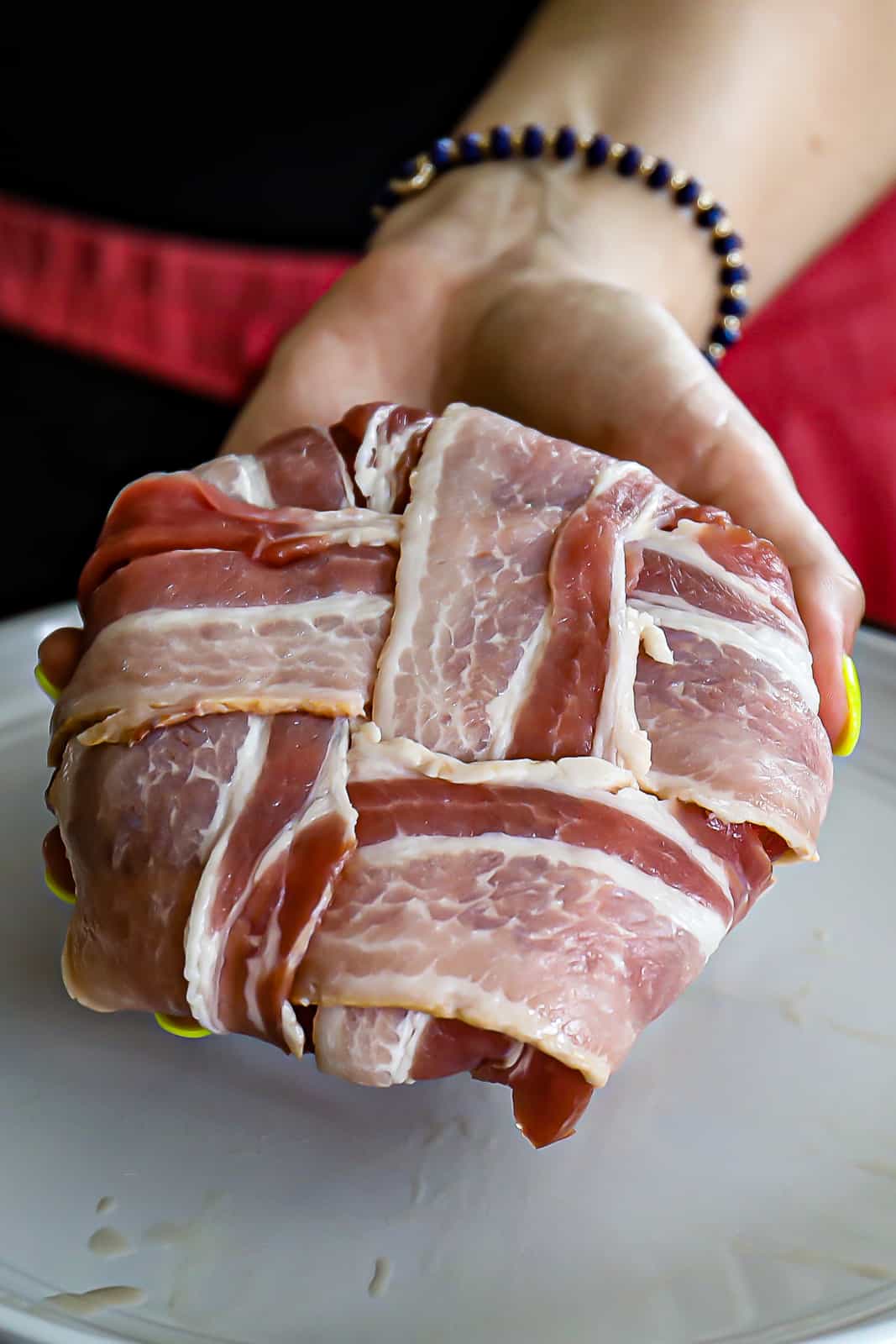 Hand Holding A Bacon Weave Wrapped Burger Stuffed With Cheese