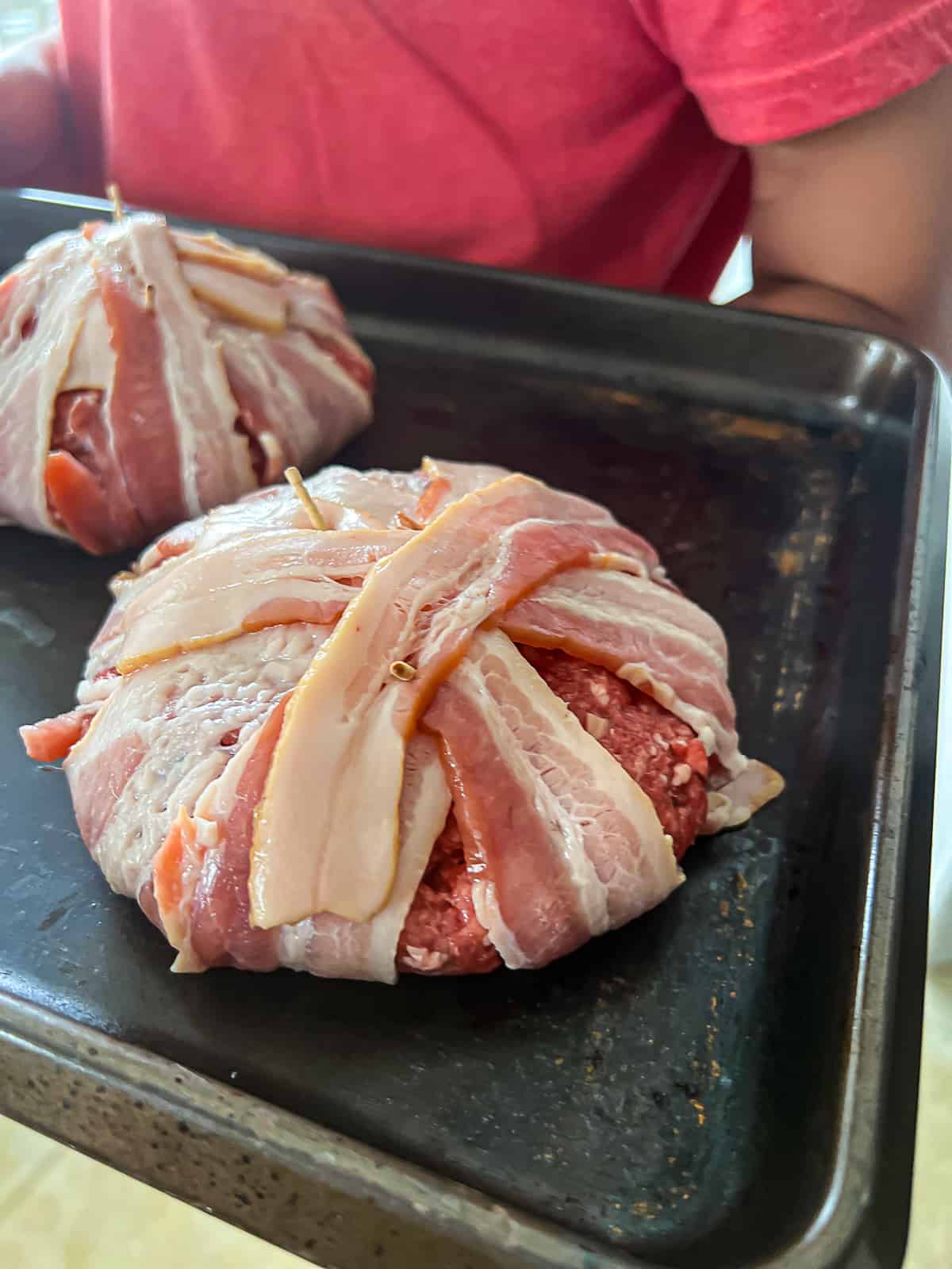 Raw Bacon Wrapped Around Burger Patties On A Baking Sheet
