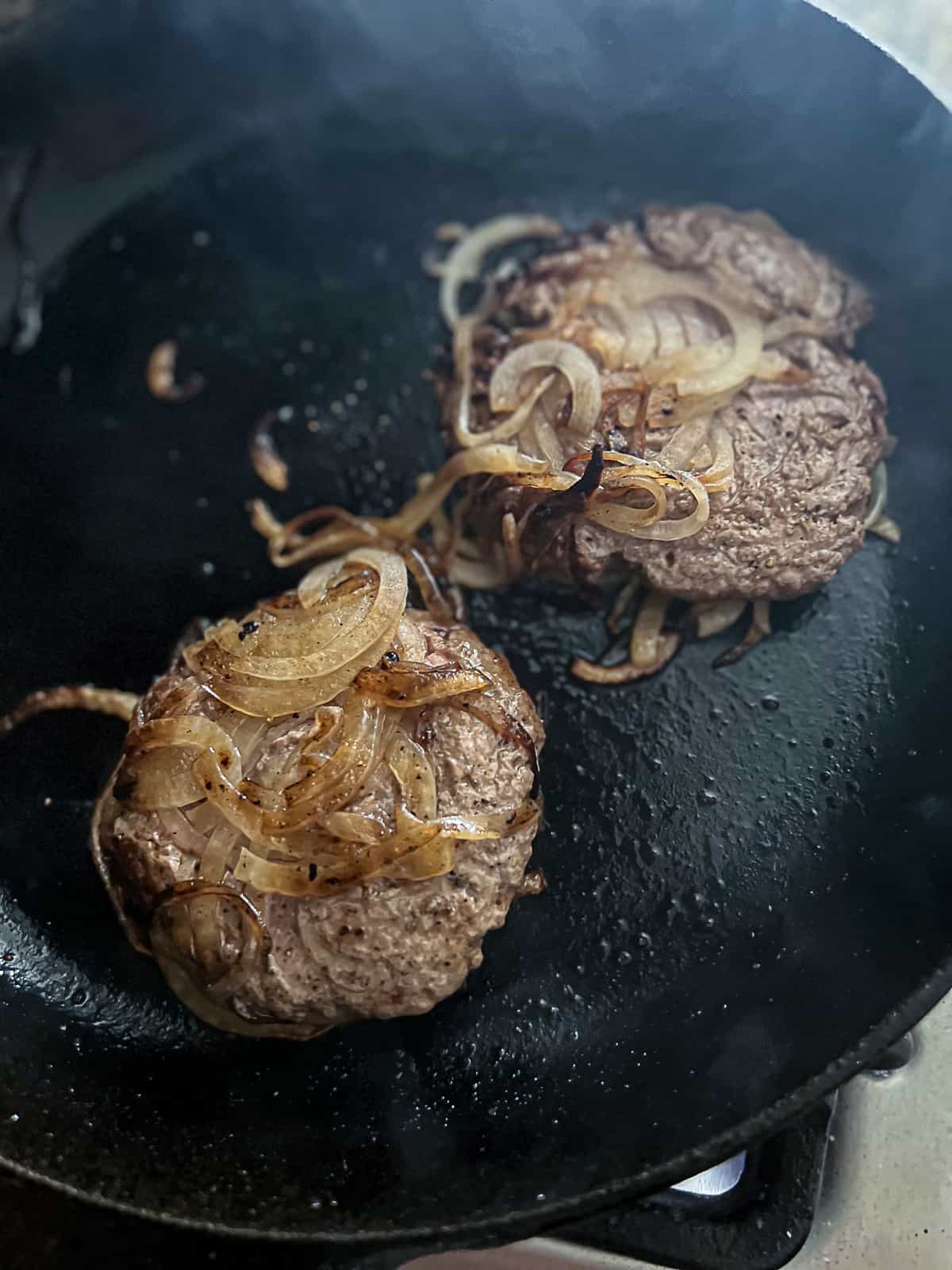 Searing Burger Smashed In Onions in Cast Iron Skillet