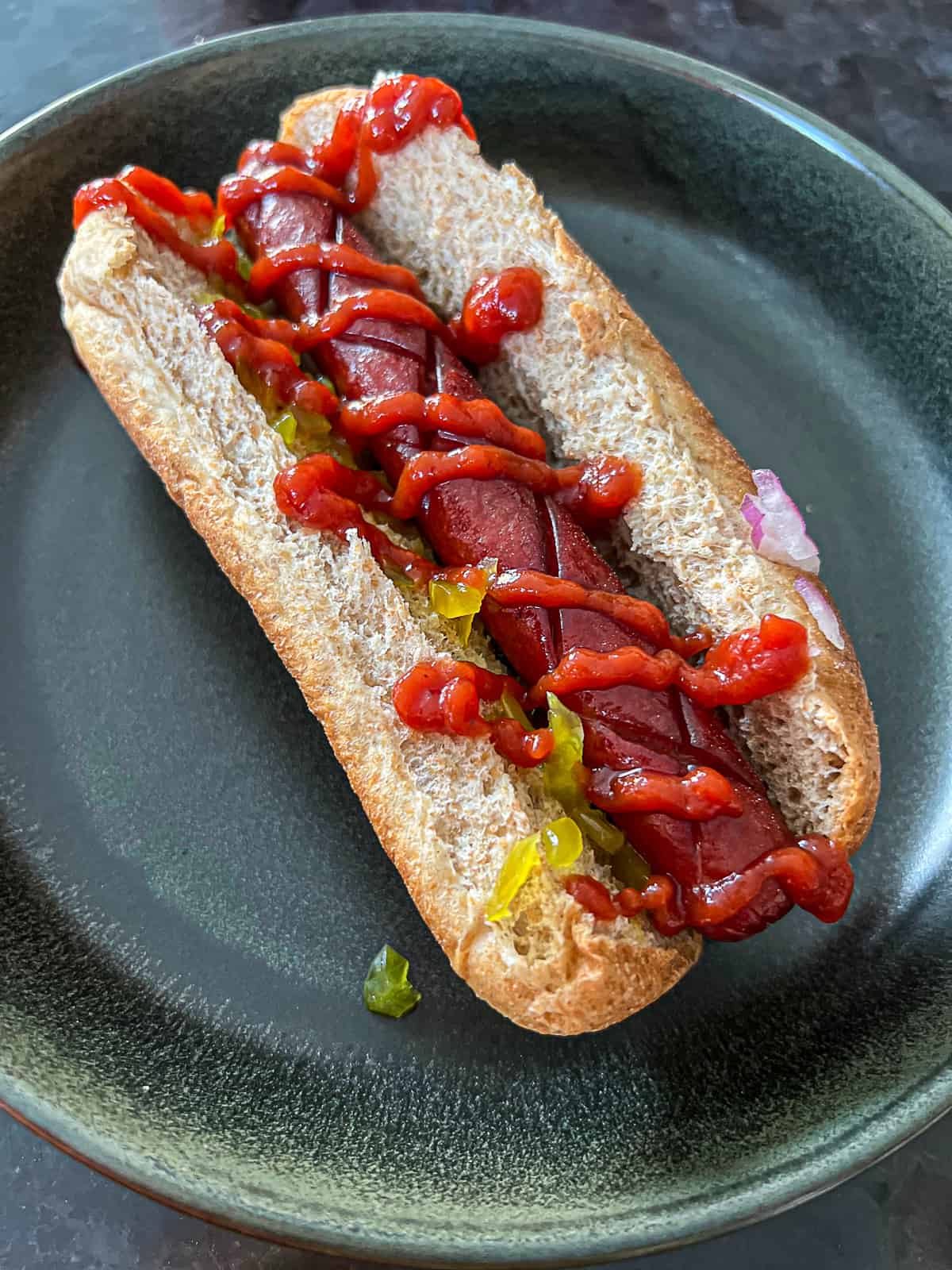 Smoked Traeger Hot Dog in bun with condiments on dinner plate 