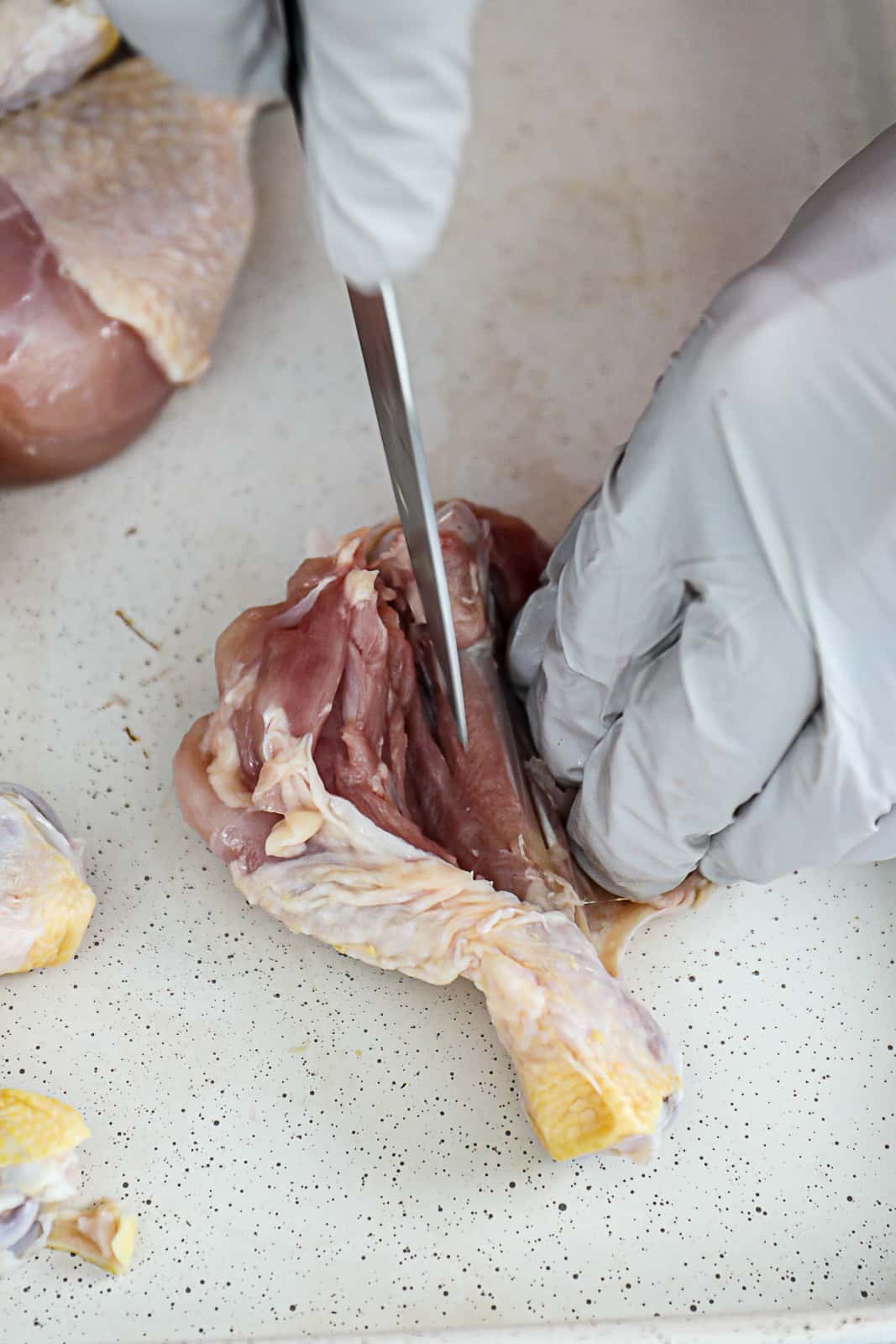 Butterfly slicing chicken legs with a pairing knife