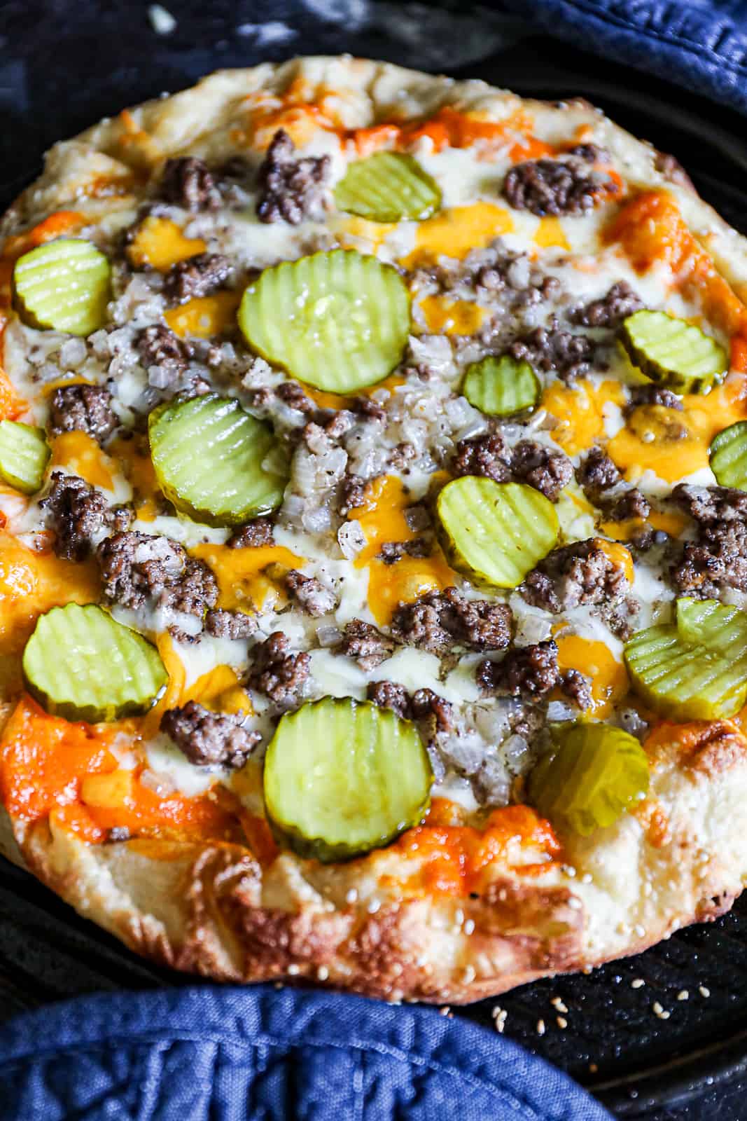Closeup of Pizza with pickles, cheeseburger meat, and sesame seeds