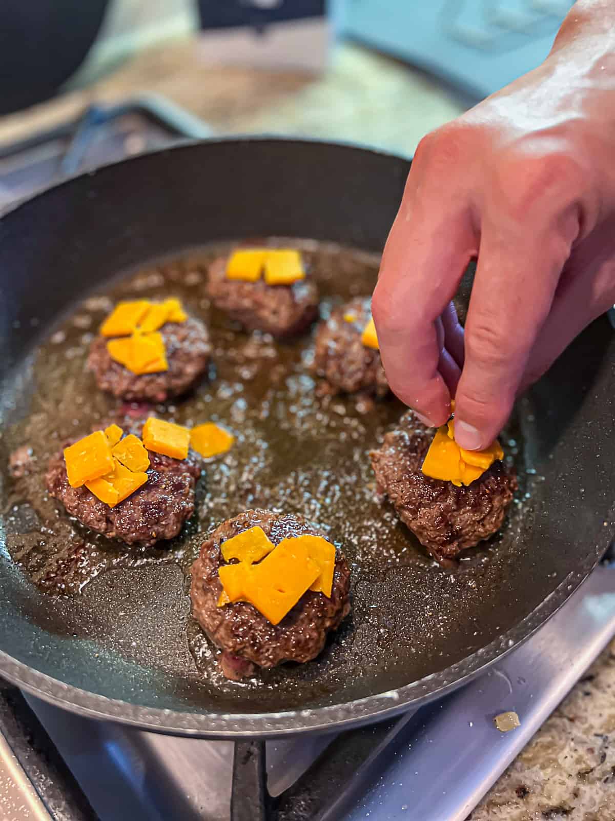 Cooking burger sliders with cheese on the stove