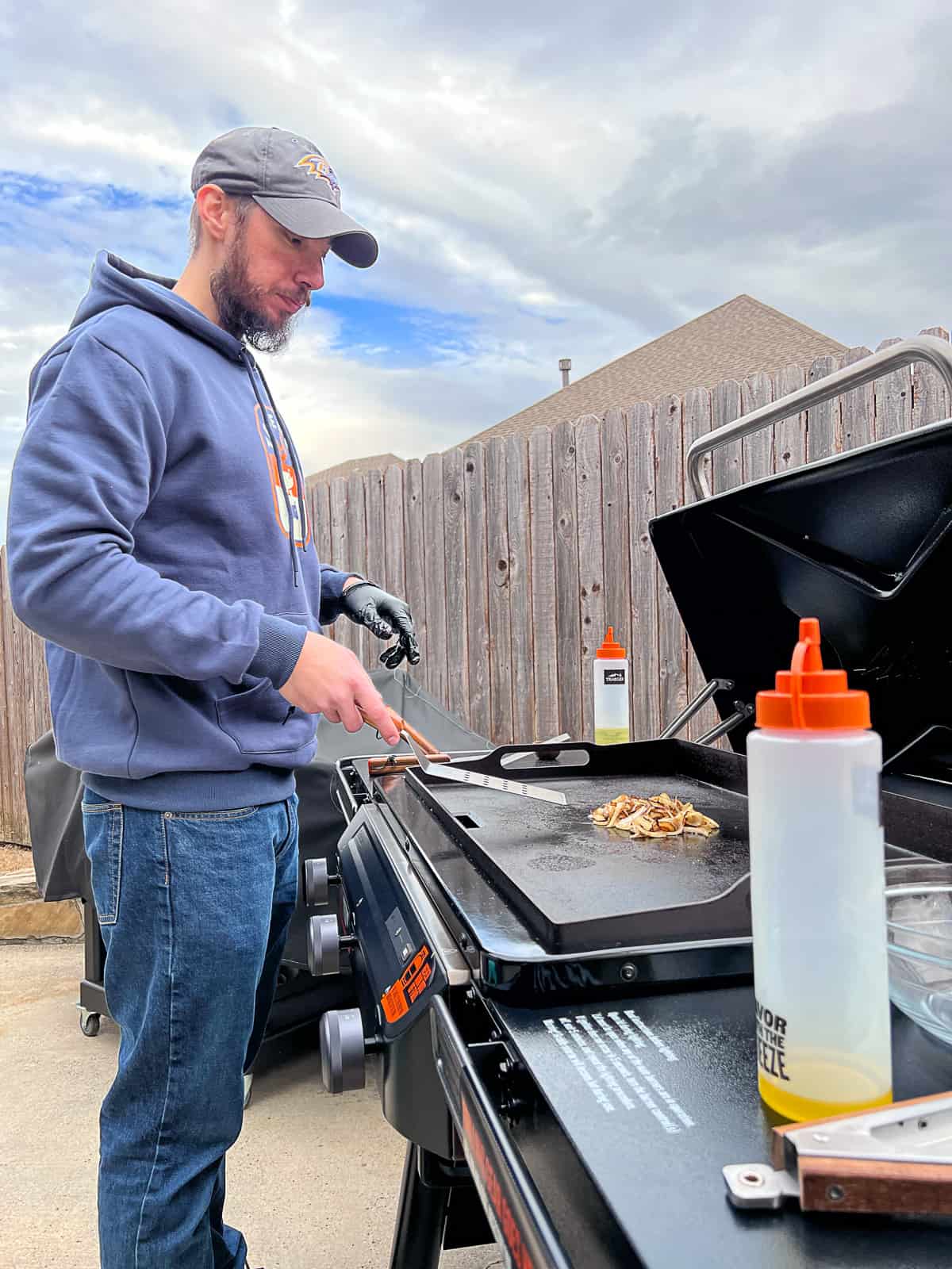 Man Cooking Griddle Onions Recipe on Traeger Flatrock Grill