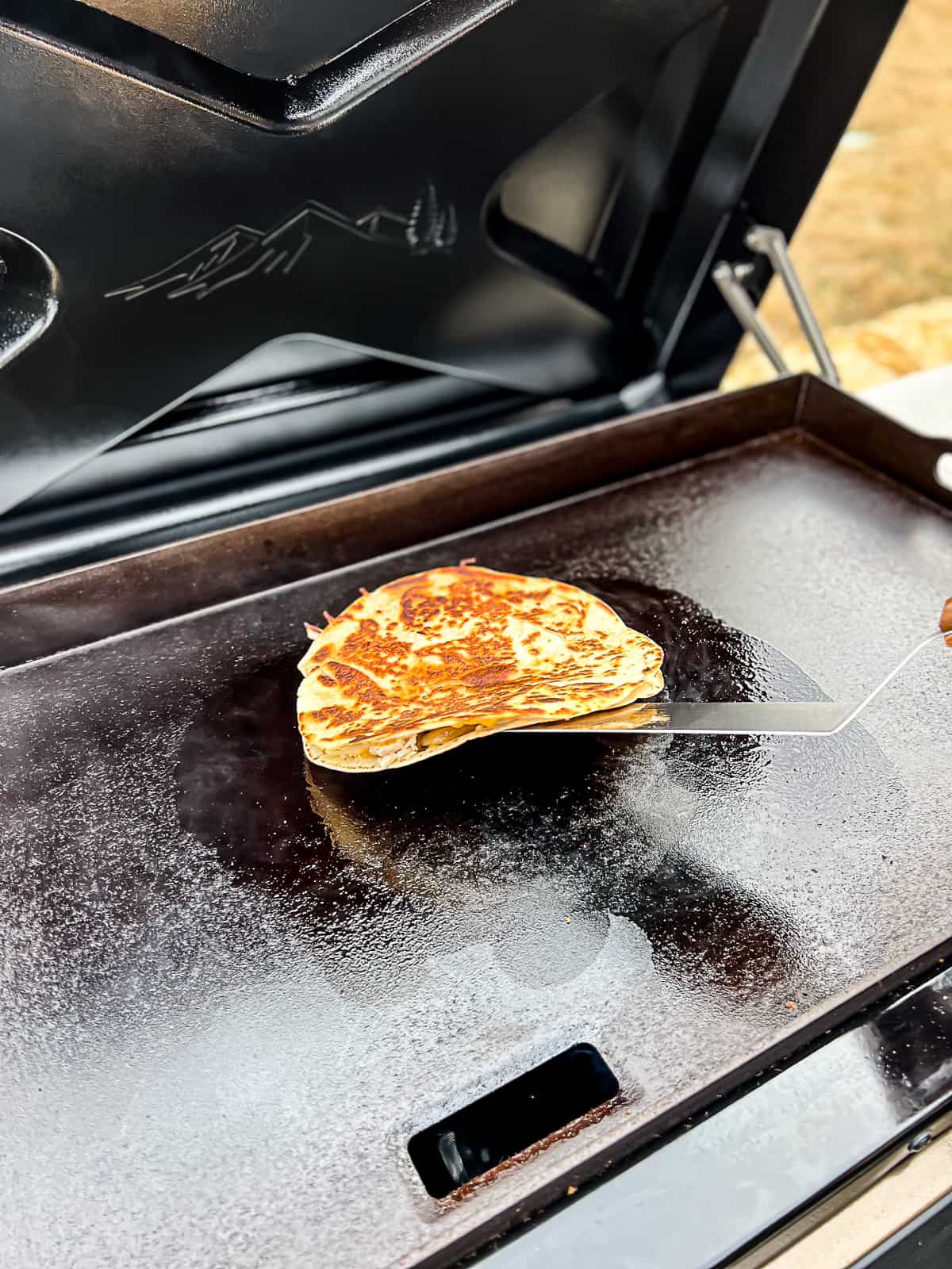 Melted cheese inside quesadilla cooking on a Traeger Flatrock griddle grill