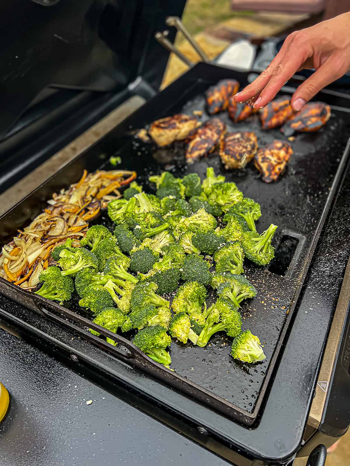 Griddle cooking chicken breast with broccoli and onions on the Flatrock Traeger Griddle