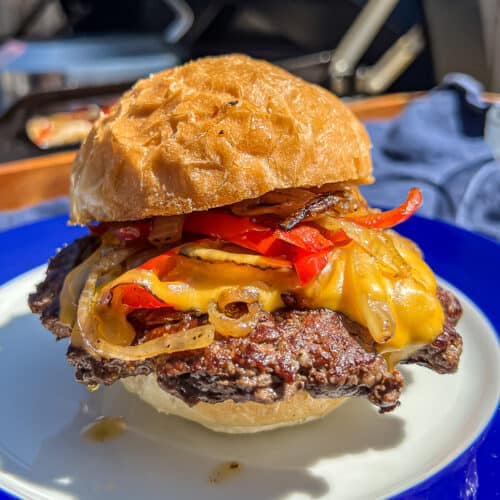 Traeger Flatrock Griddle Philly cheesesteak burgers with onions and peppers and cheddar cheese