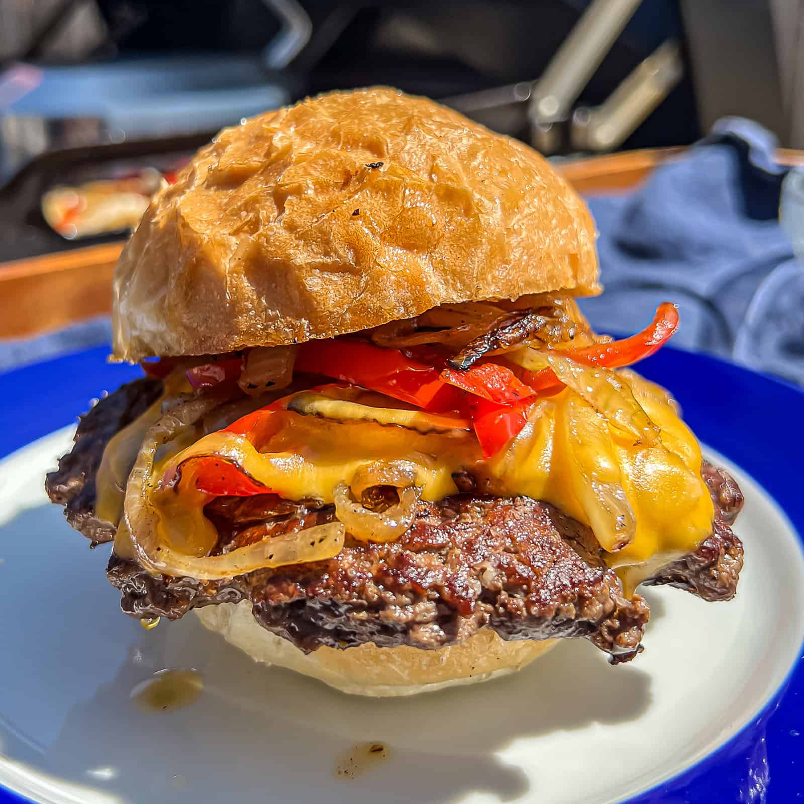 https://sipbitego.com/wp-content/uploads/2023/03/Traeger-Flatrock-Griddle-Philly-cheesesteak-burgers-with-onions-and-peppers-and-cheddar-cheese-Sip-Bite-Go.jpg