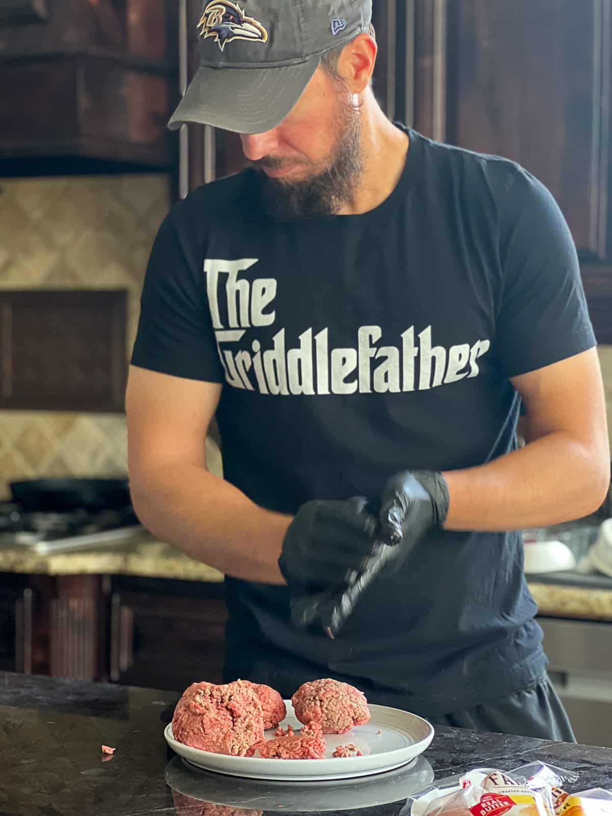 Man making smash burger patties with ground hamburger meat wearing a griddle shirt 