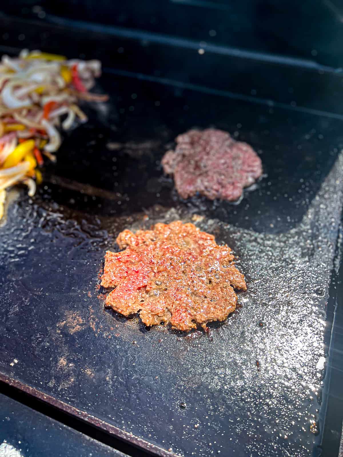 Traeger Flatrock Griddle Cooking Breakfast Burgers Smashed on the flattop with onions and peppers 