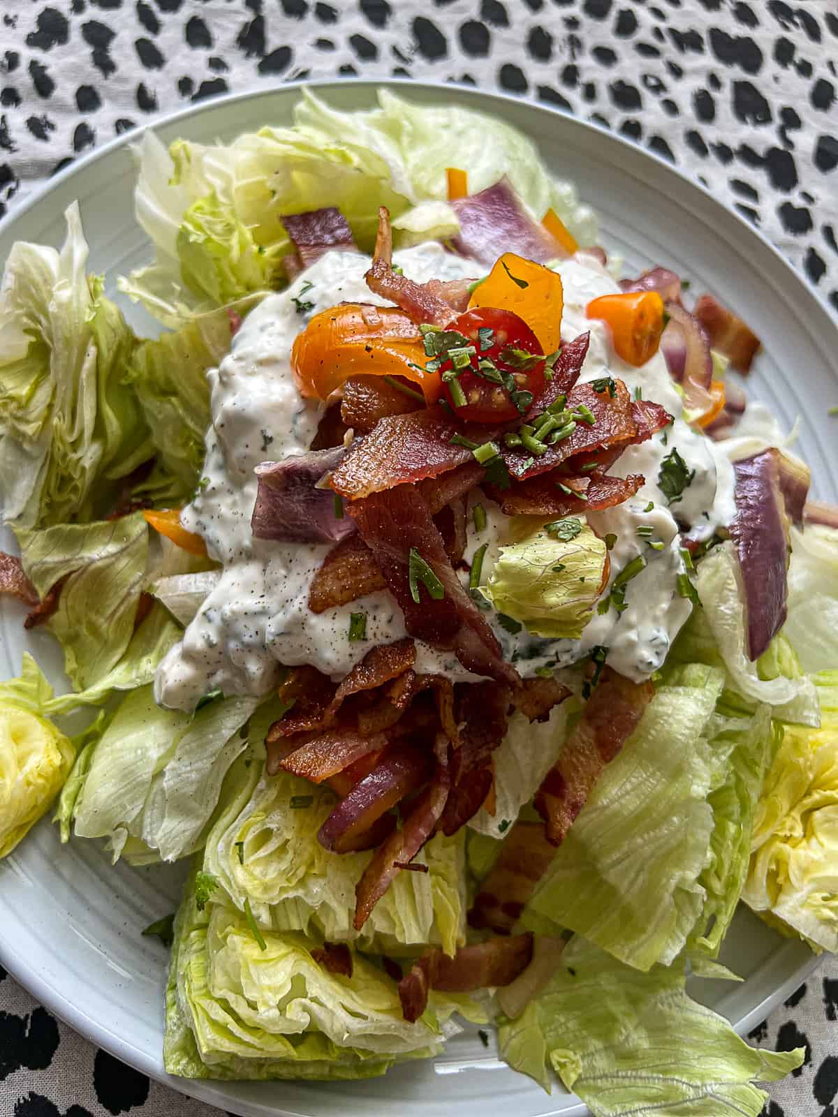 blue cheese dressing with bacon and vegetables on a wedge salad