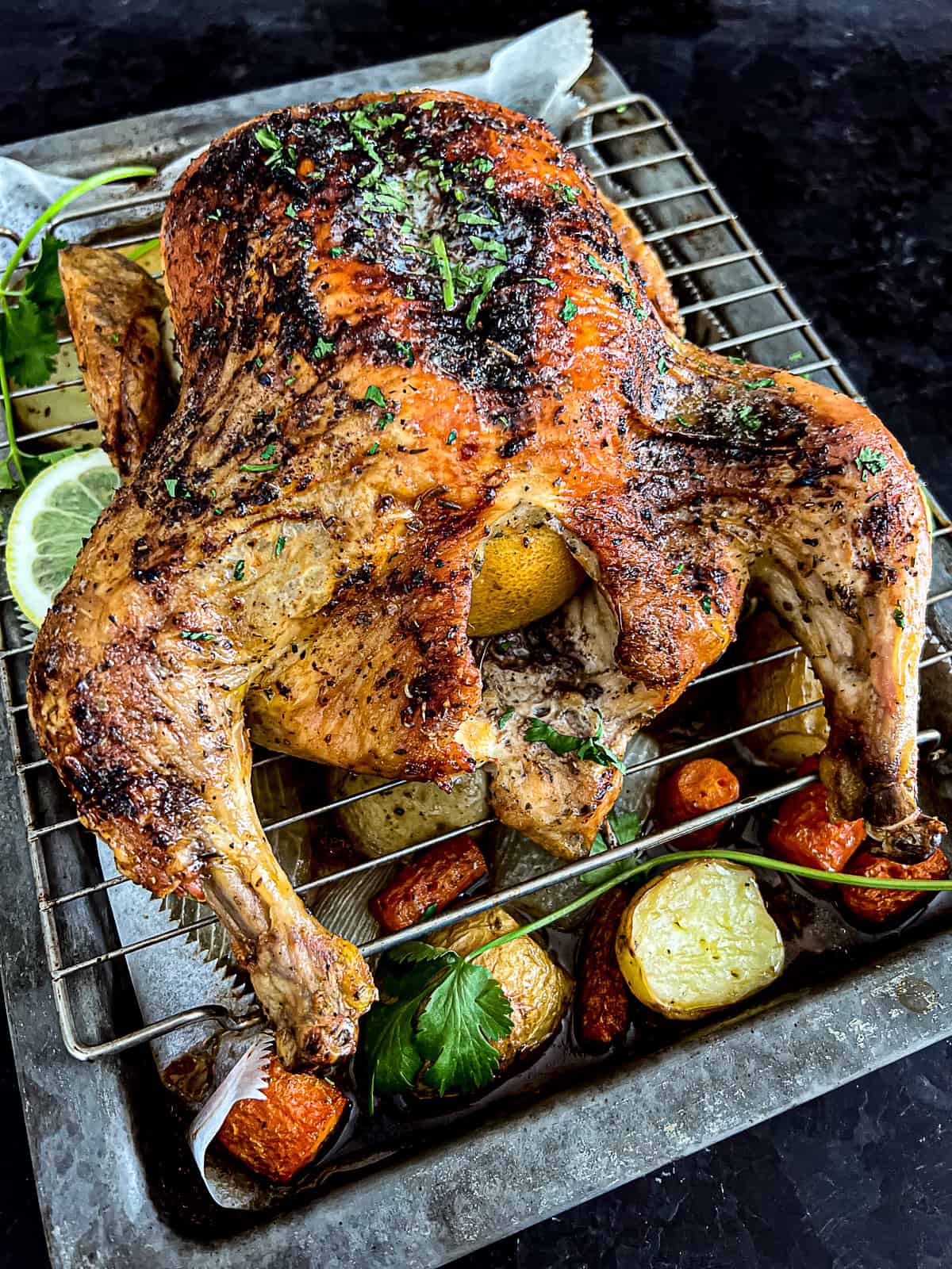 Resting Roasted Whole Chicken on a sheet tray with vegetables and potatoes