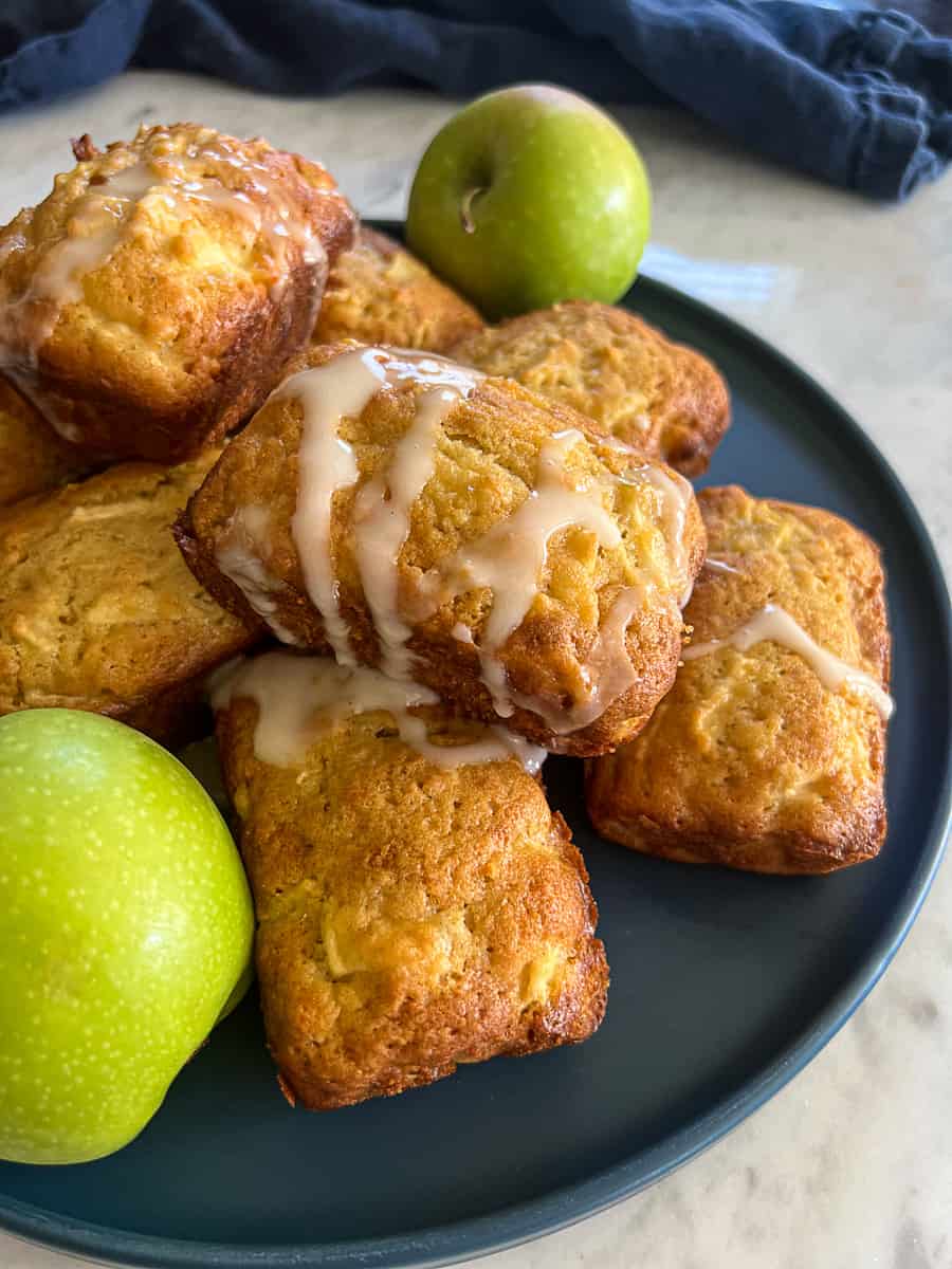 Apple Bread Mini Loaves with Cider Icing on a dessert platter with green apples