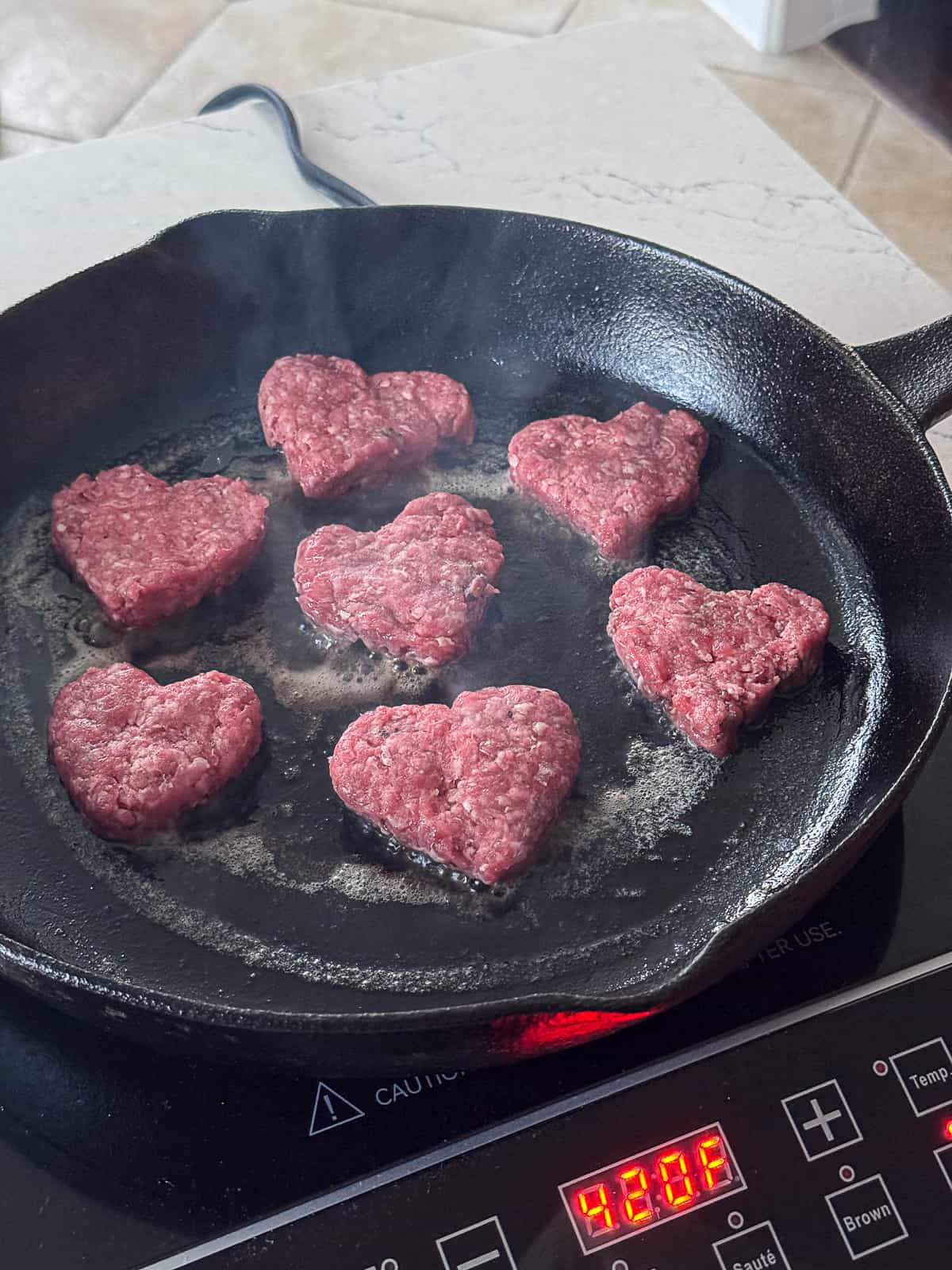 Browning Heart Shaped Burgers in a cast iron skillet