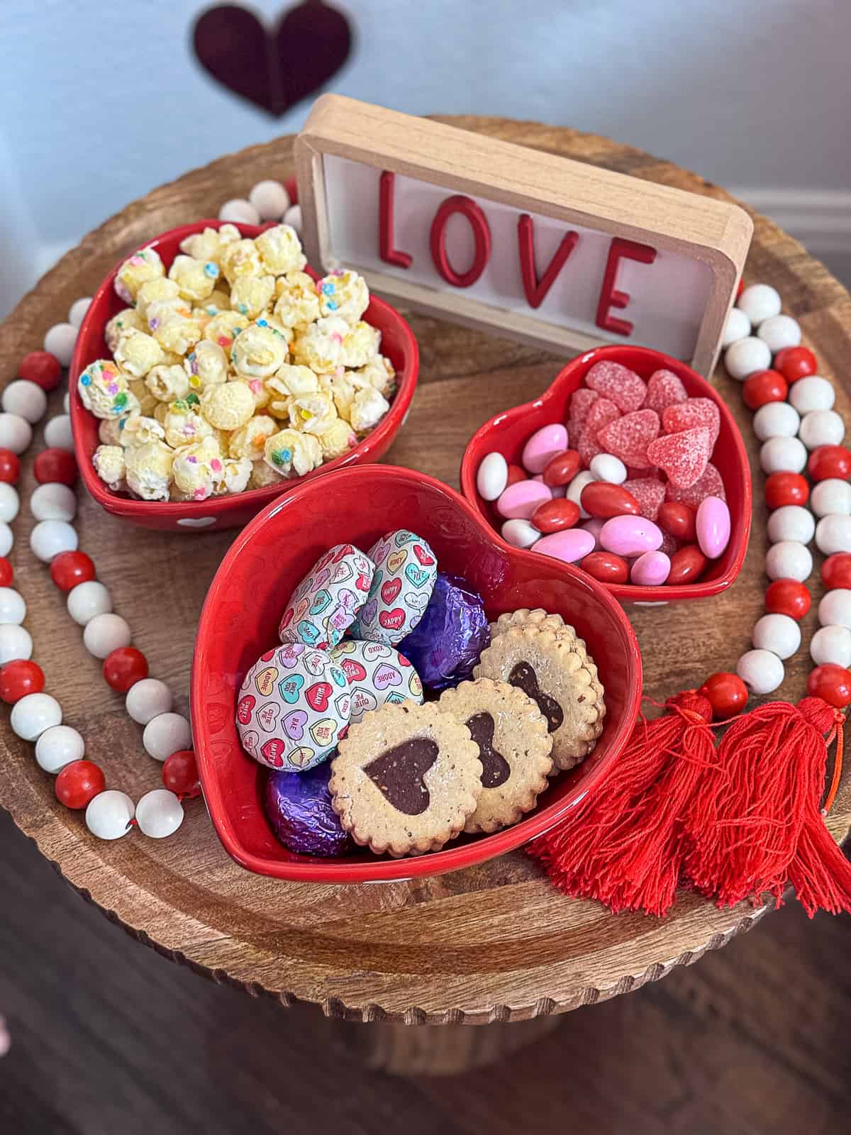 Valentine's Day entryway table with heart snack bowls filled with chocolate and treats