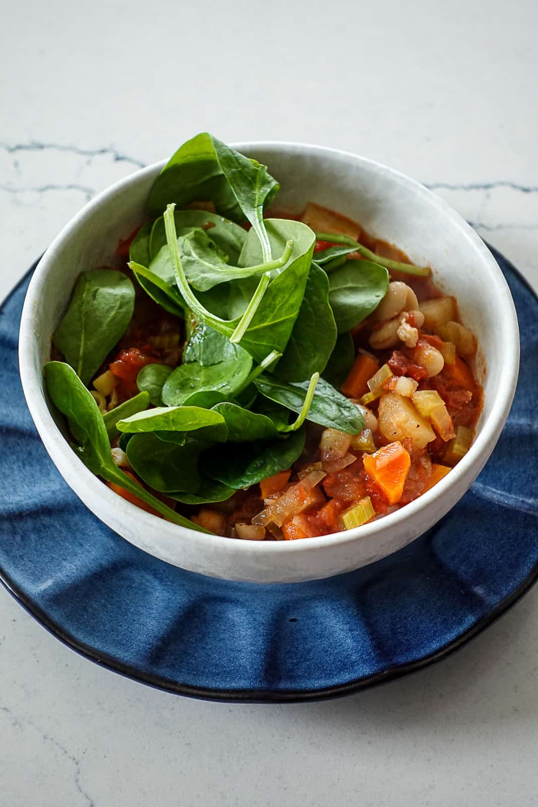 Fresh spinach added to Minestrone Soup in a bowl