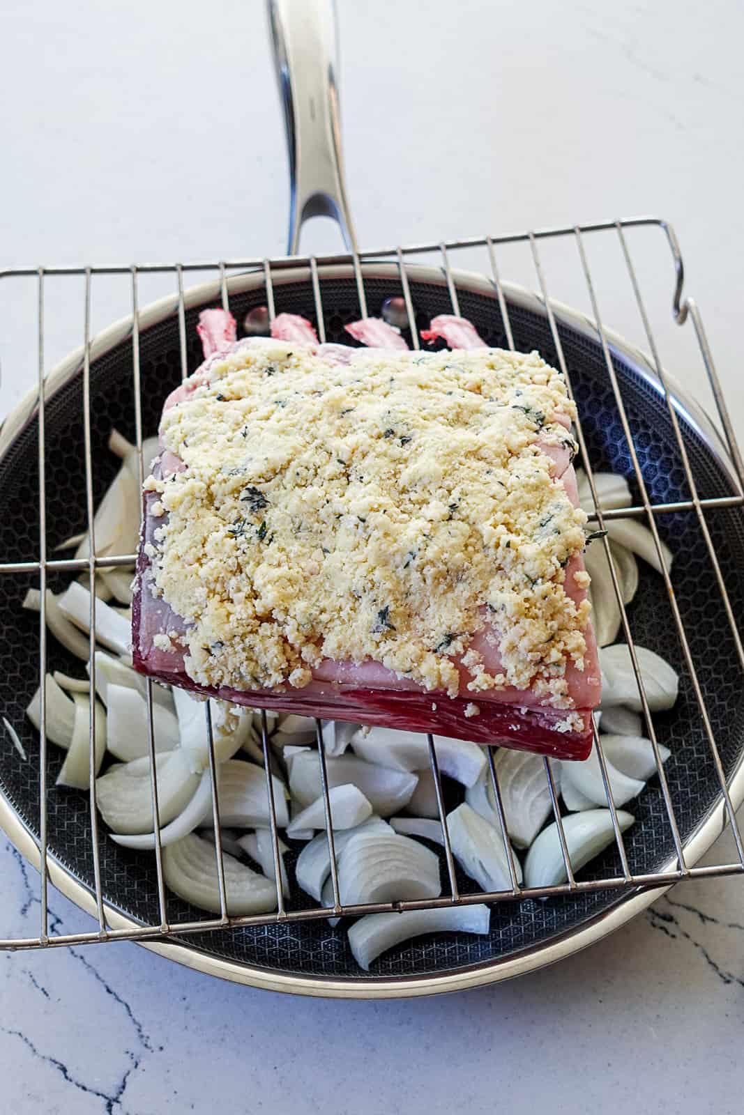 Rack of lamb with crust on top of onions in a pan