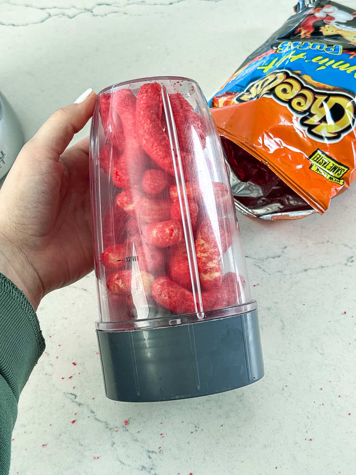 Holding a blender filled with Flamin' Hot Cheetos Snack