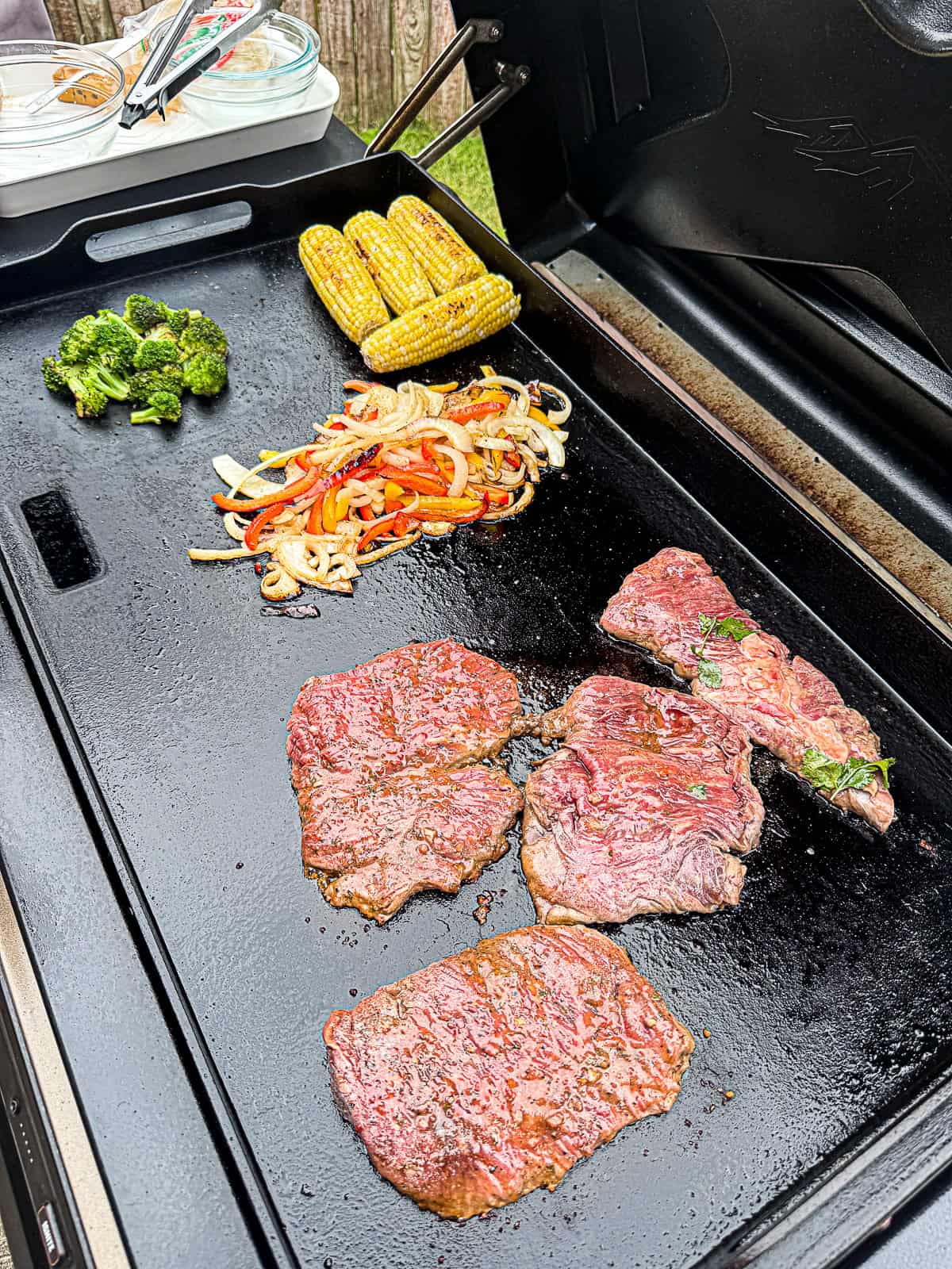 Griddle cooking skirt steak family dinner with meat and vegetables