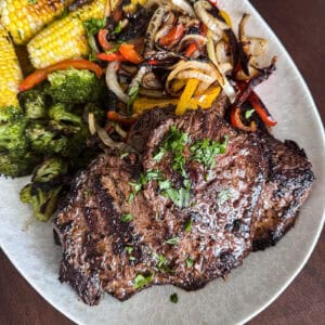 Griddled skirt steak family dinner with corn broccoli and peppers and onions