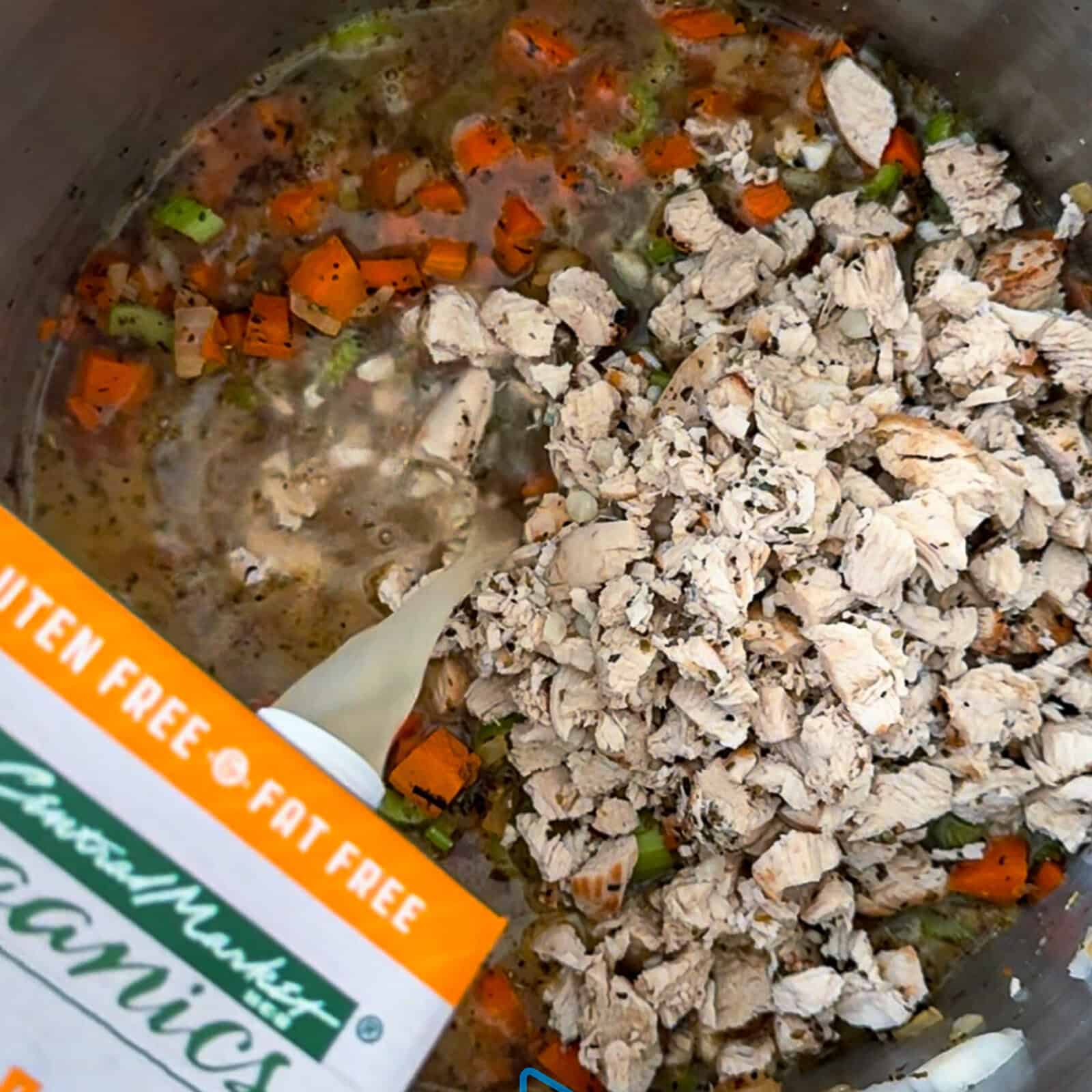 Simmering homemade chicken noodle soup with chicken broth in a large pot