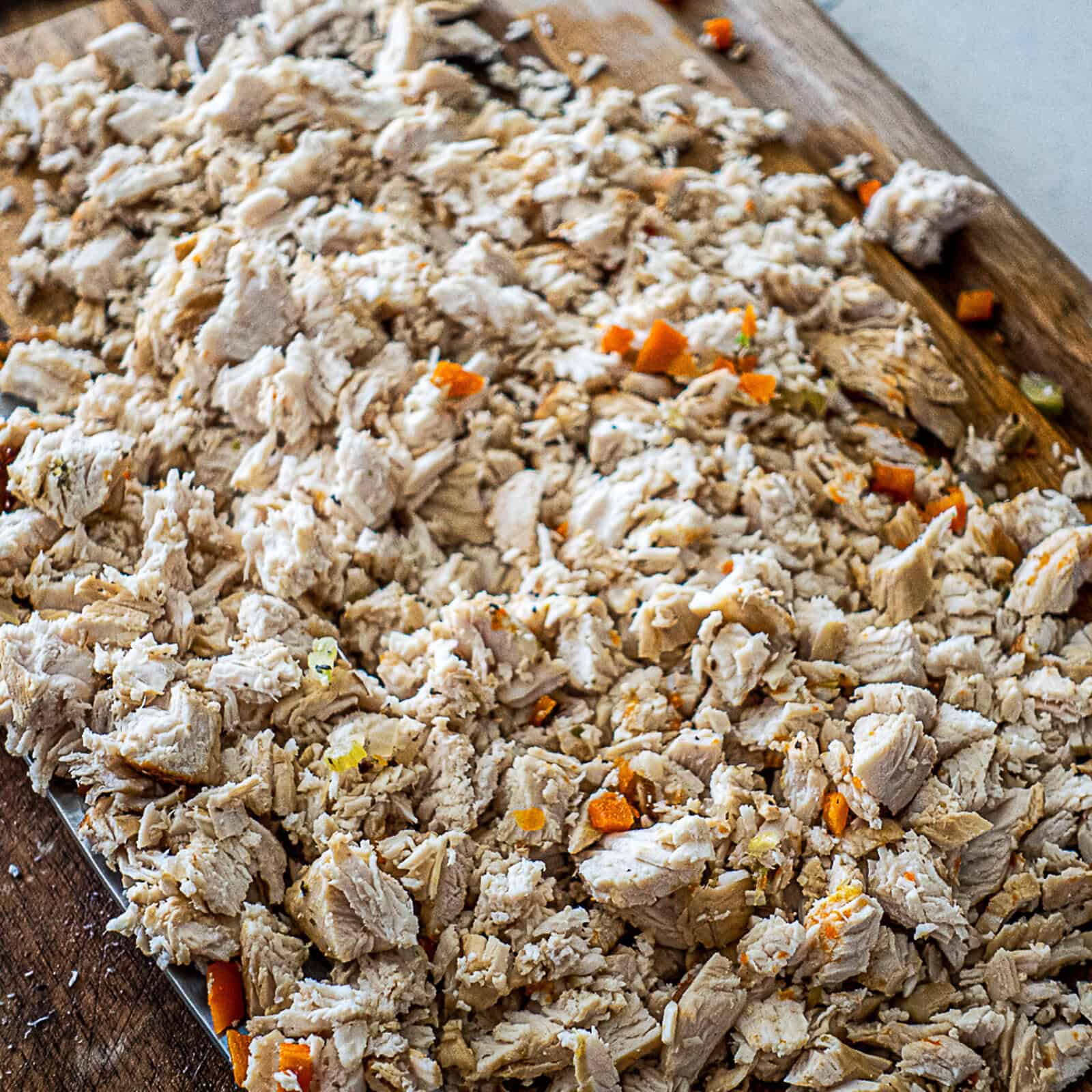 Finishing homemade chicken noodle soup by dicing cooked chicken breast