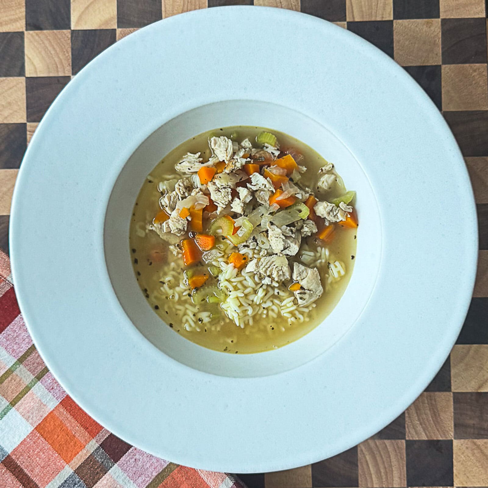 Serving homemade chicken noodle soup in white soup bowls with herbs