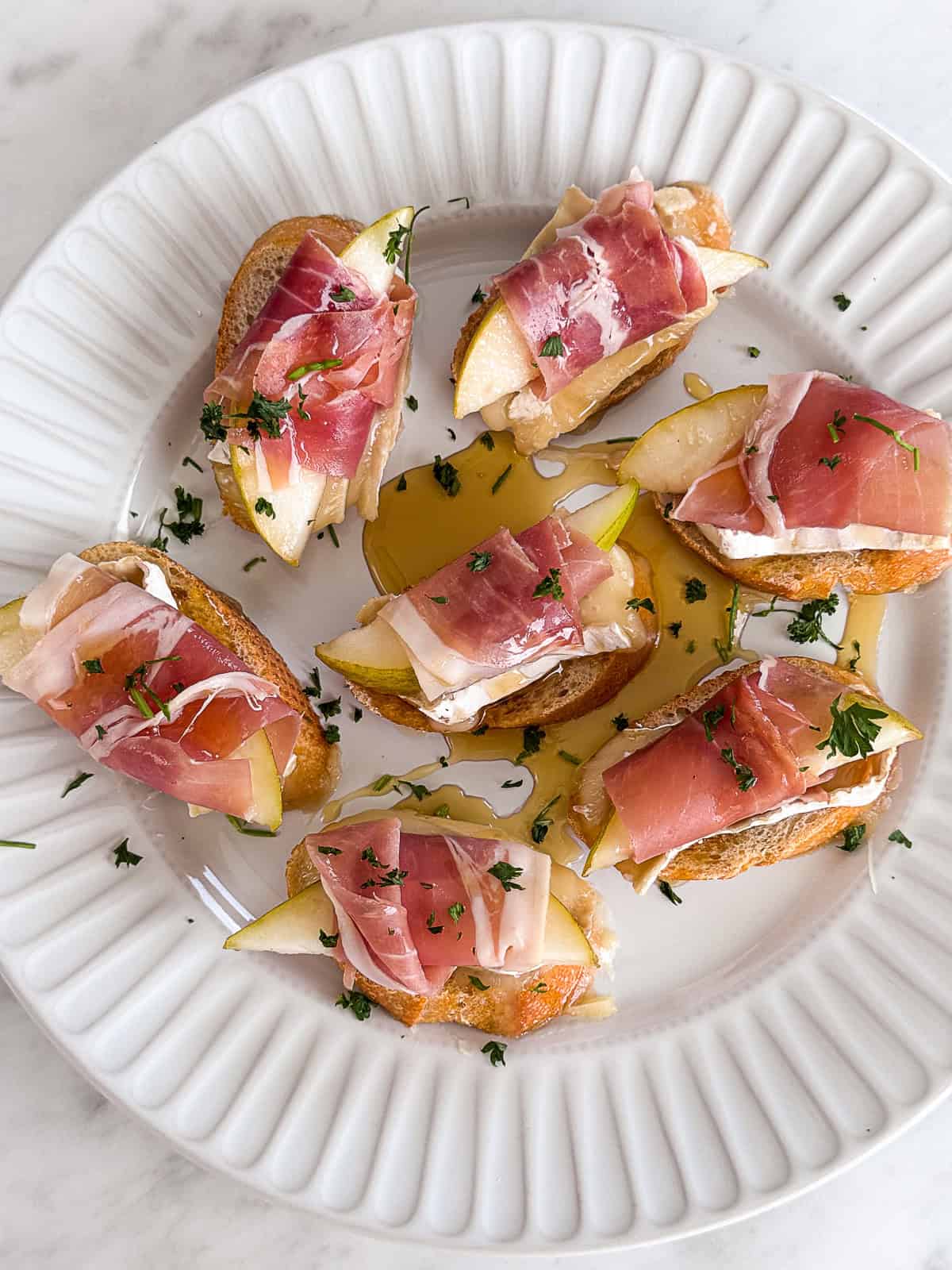 لوحة من المقبلات مع Brie Pear و Prosciutto Crostini
