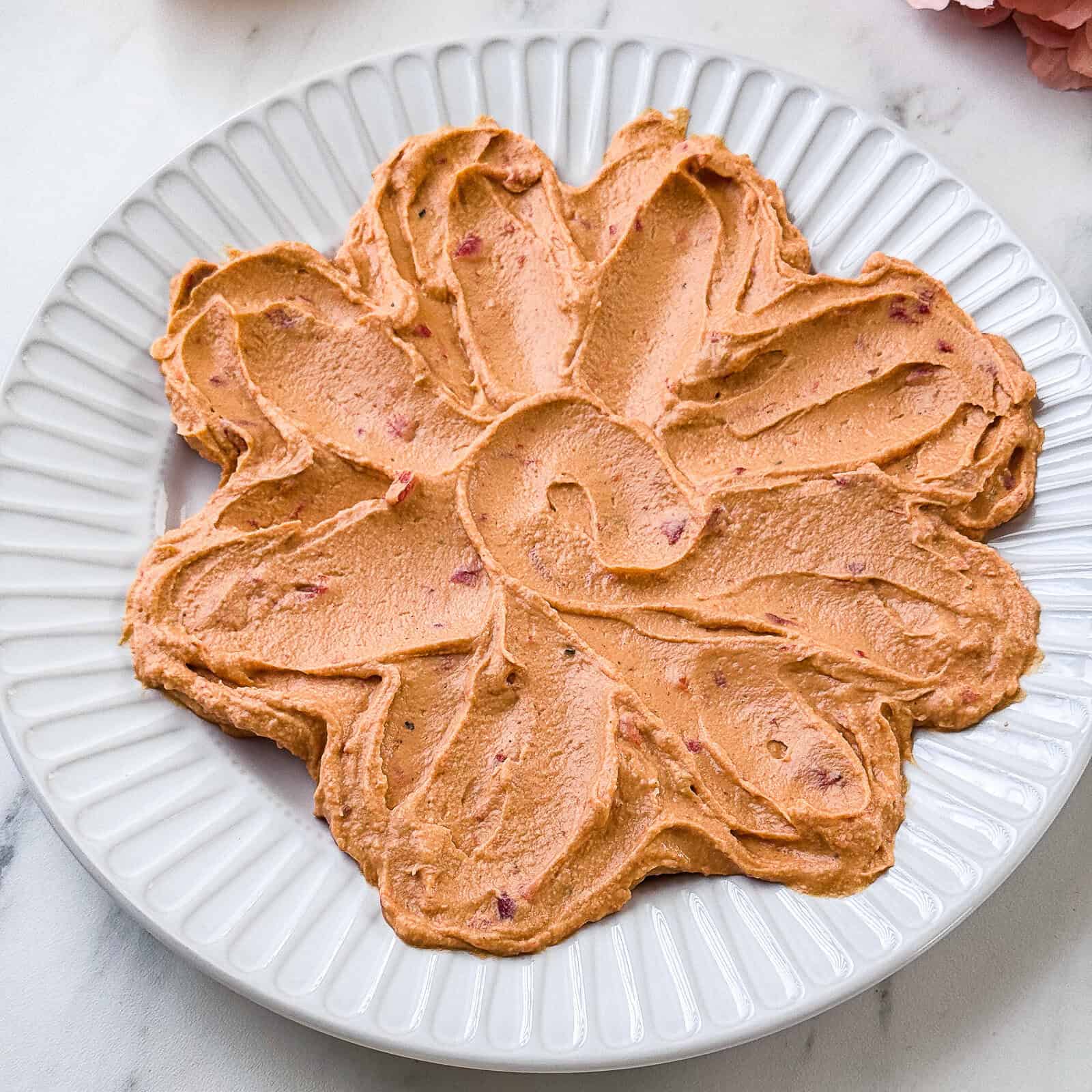 Spreading hummus into petal shapes on a plate using the back of a spoon