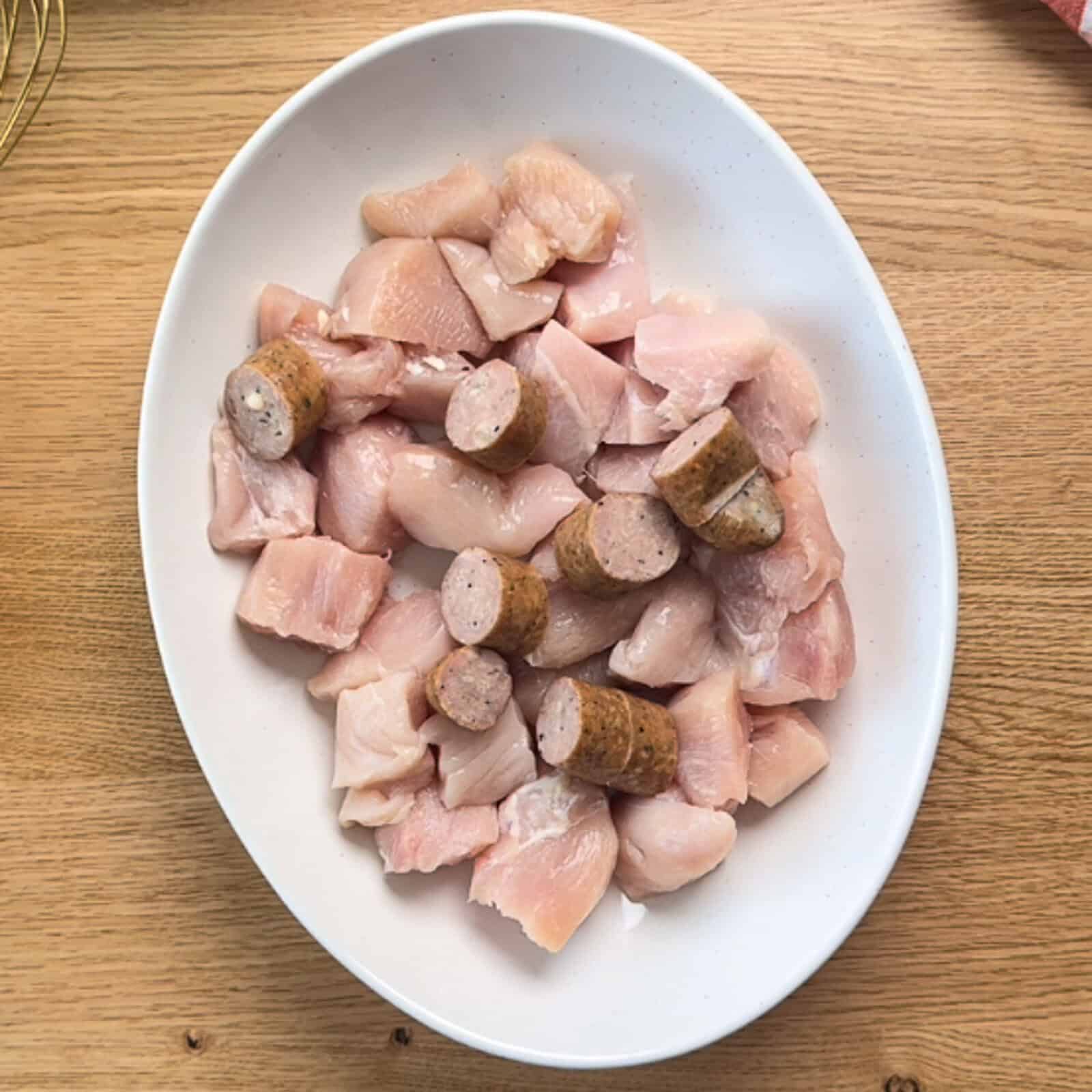 Step 1 Raw sausage and chicken chunks in a mixing bowl