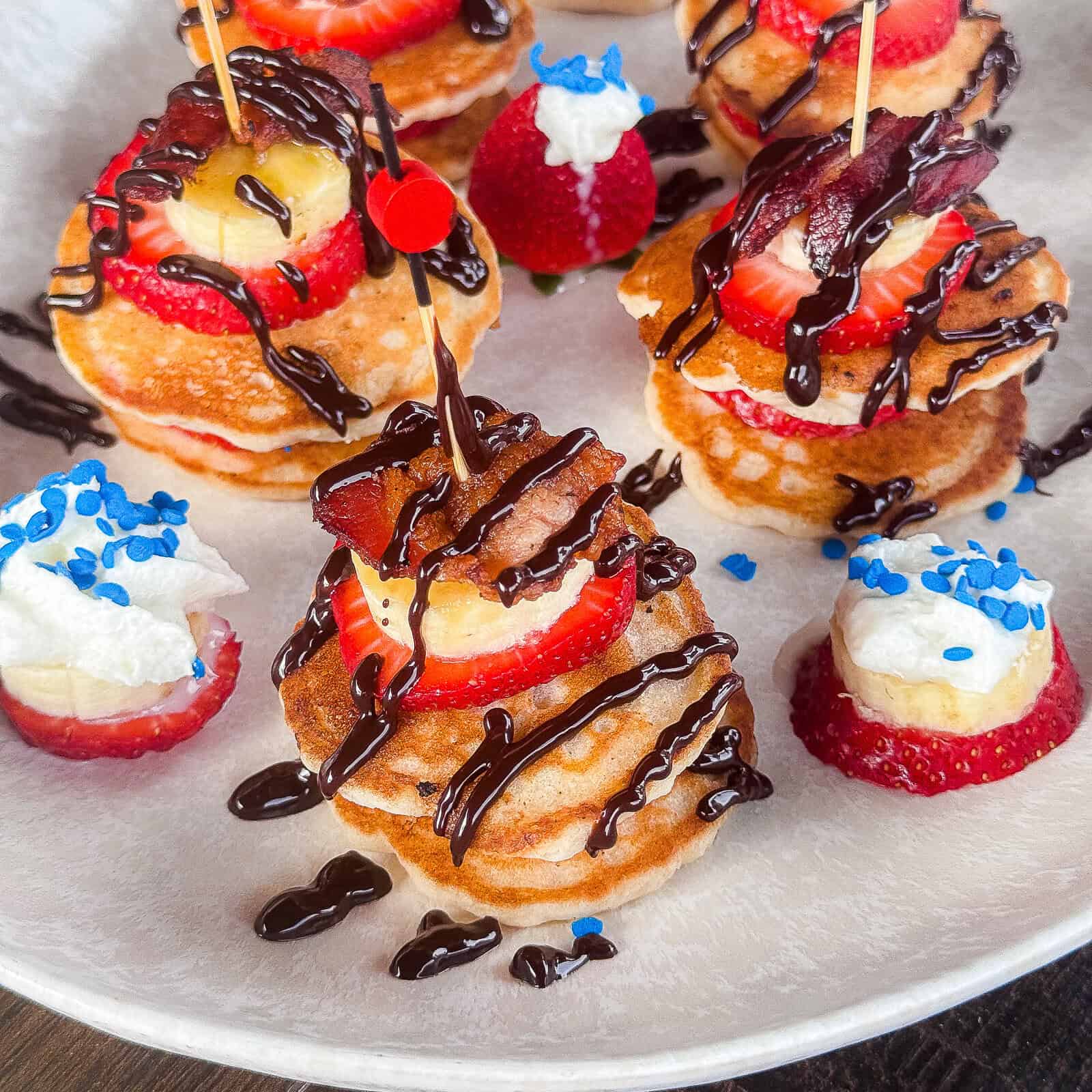 Serving mini pancake skewers with fruit and bacon on brunch platter