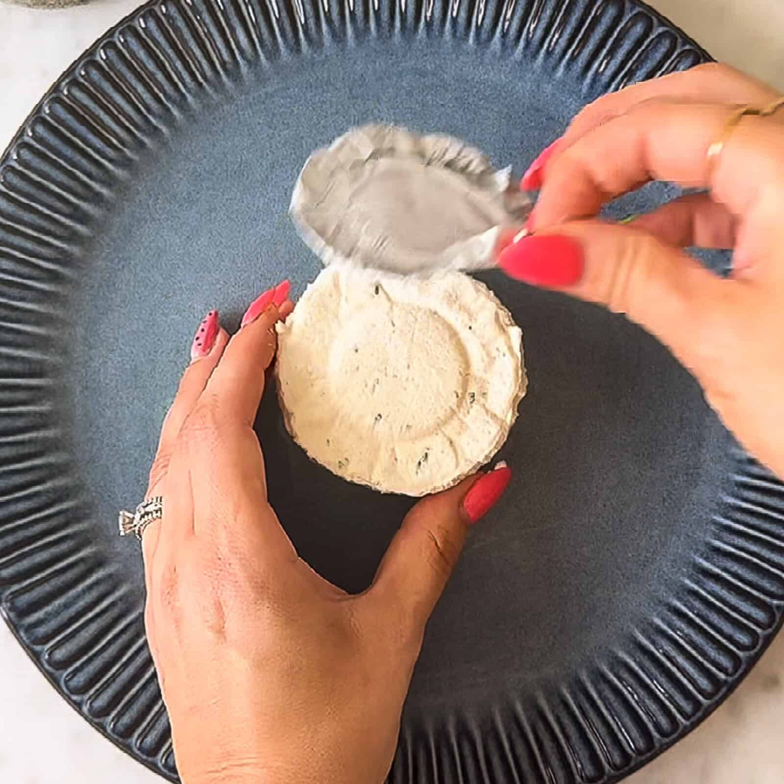 Boursin cheese puck centered on a white serving plate ready for garnish