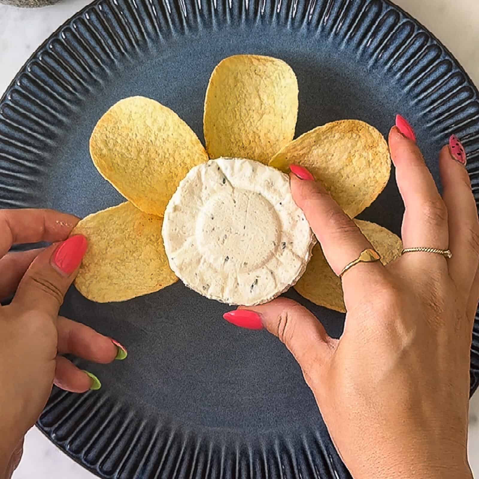 placing Pringles chips around a Boursin cheese puck on a serving plate