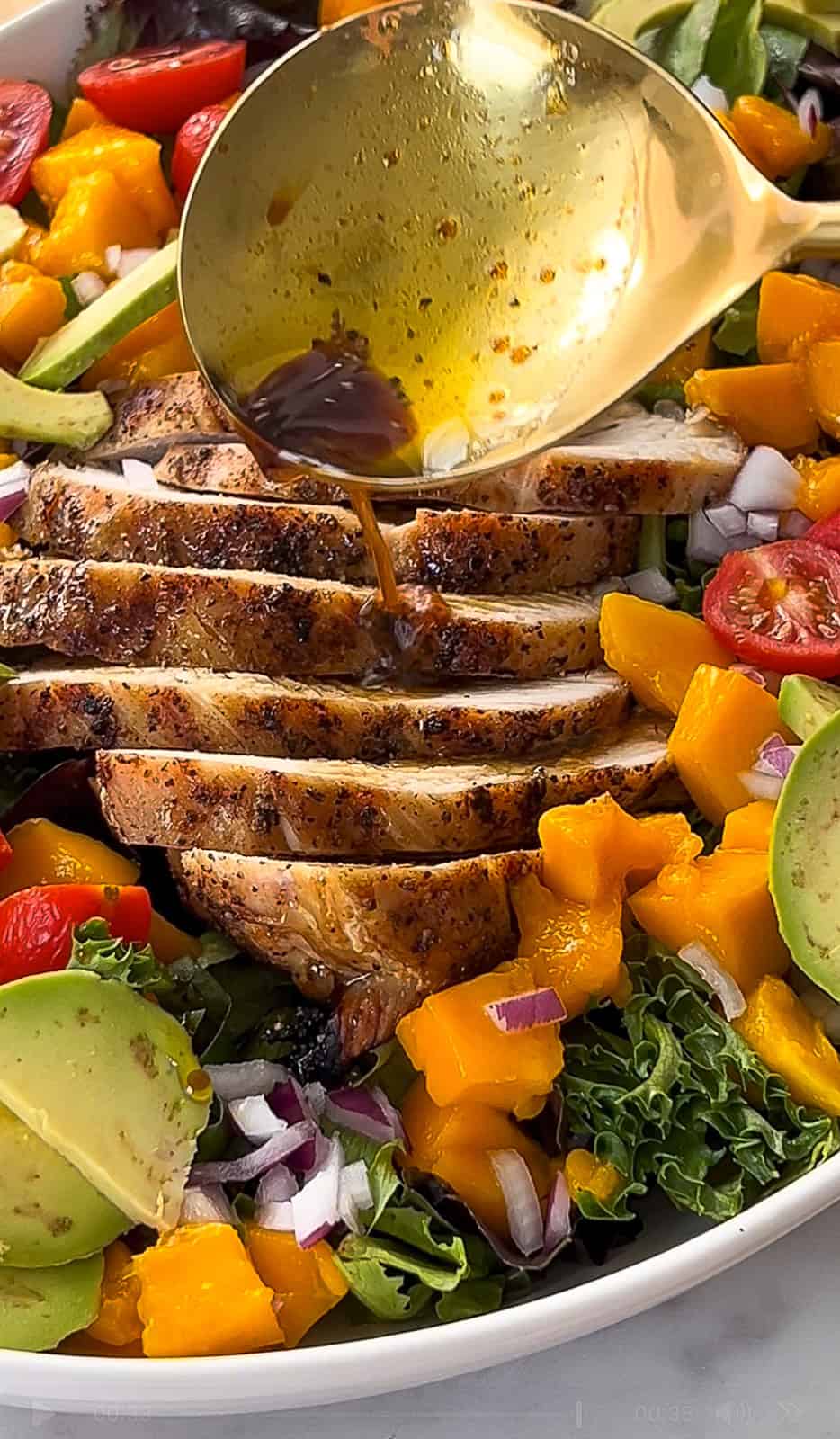 Drizzling balsamic dressing on grilled chicken mango salad