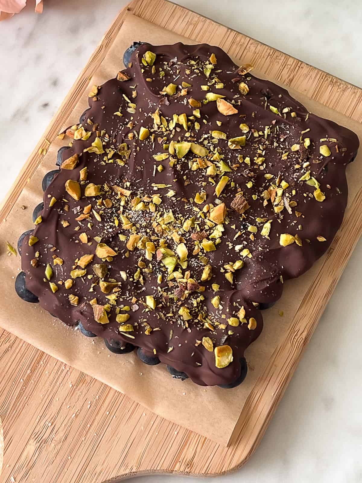 Frozen blueberries topped with chocolate, salt, and pistachios