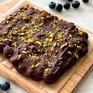 Frozen chocolate covered blueberries with pistachios on tray