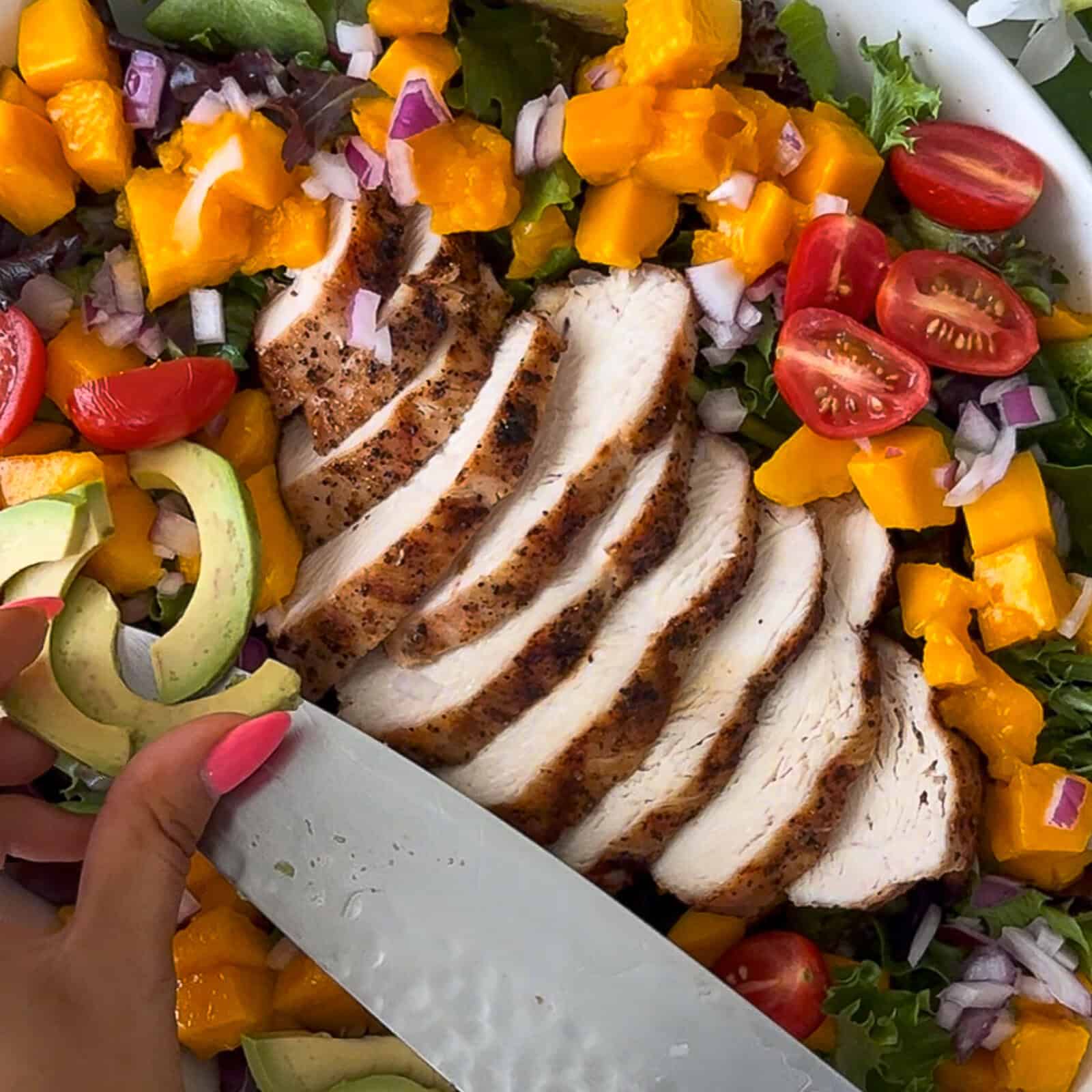 Step 4 - Topping salad with sliced chicken, mango, red onion, tomatoes, and avocado
