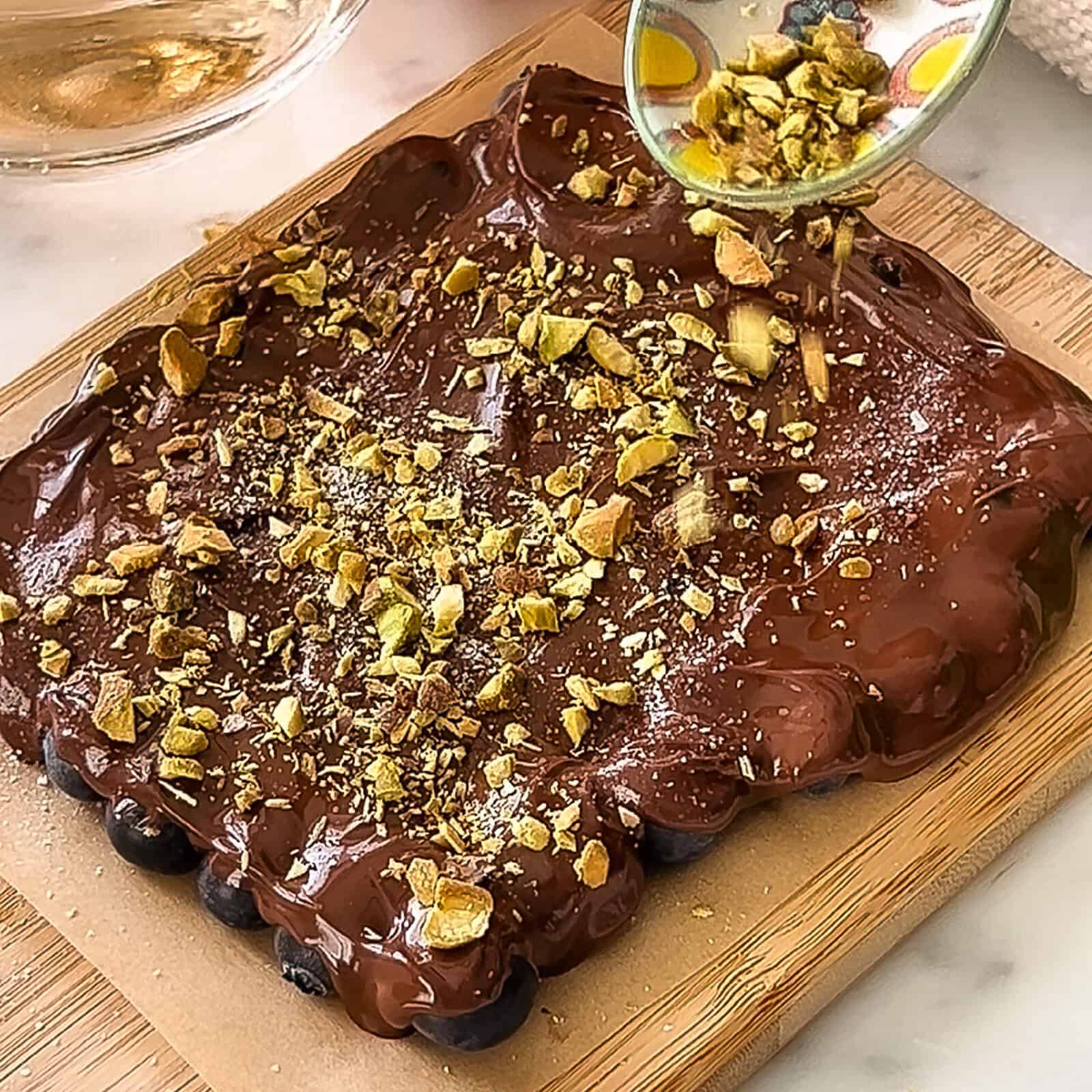 Topping melted chocolate blueberries with crushed pistachios