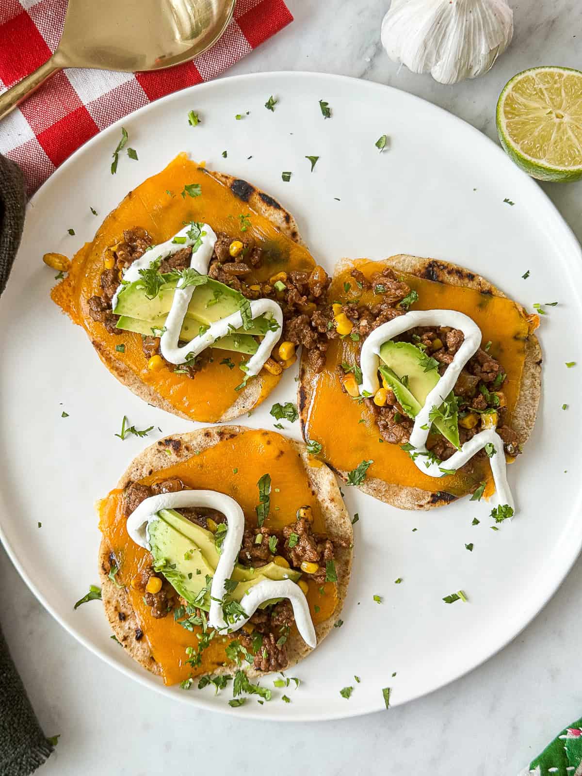 ground beef tacos with avocado and sour cream wrapped in soft butter tortillas