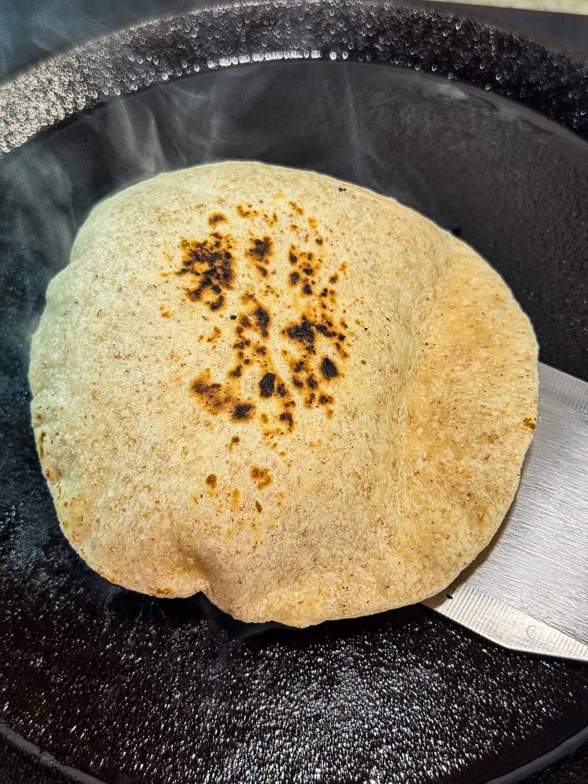 freshly cooked butter tortilla steaming on a hot cast iron skillet