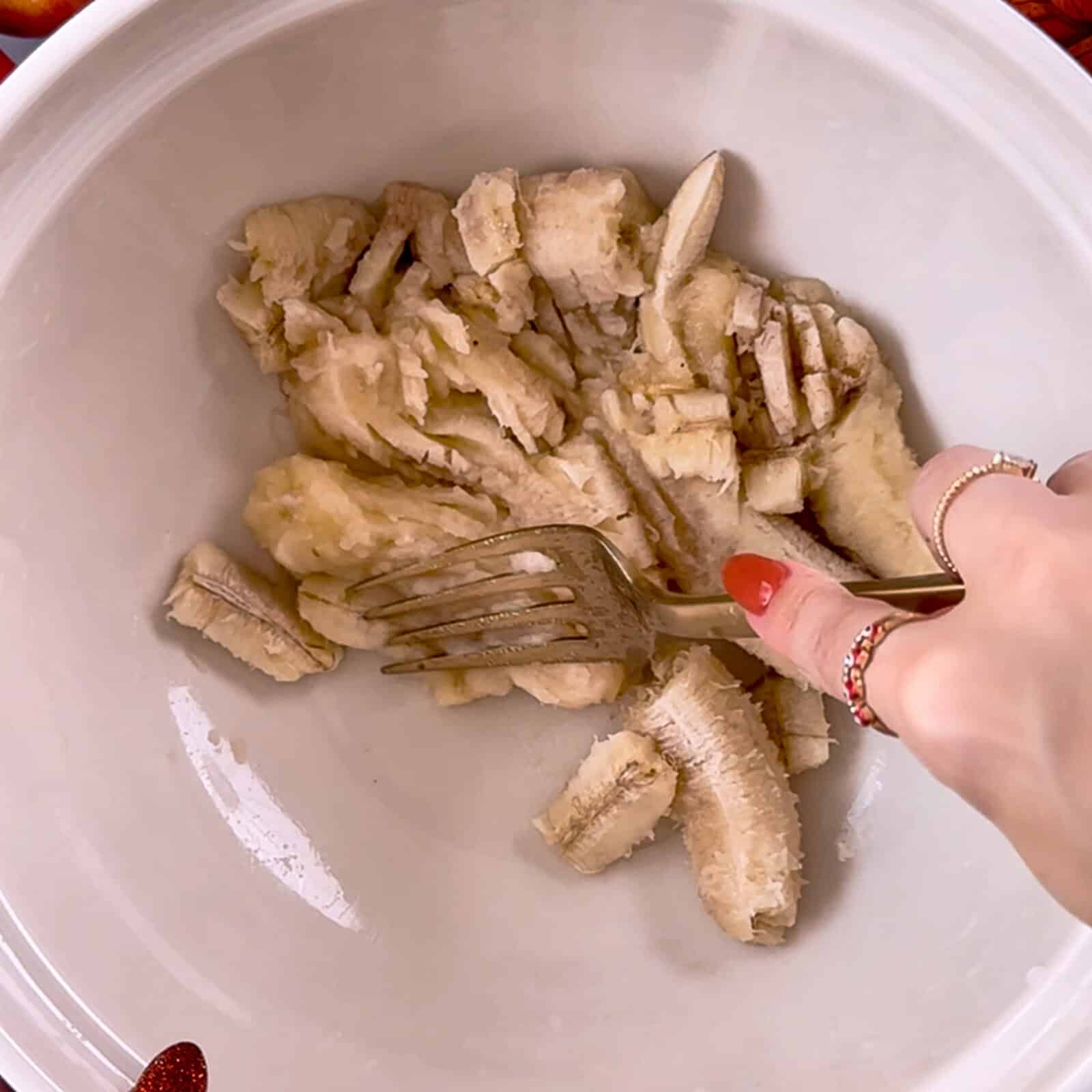 mashing ripe bananas in a large mixing bowl with a fork