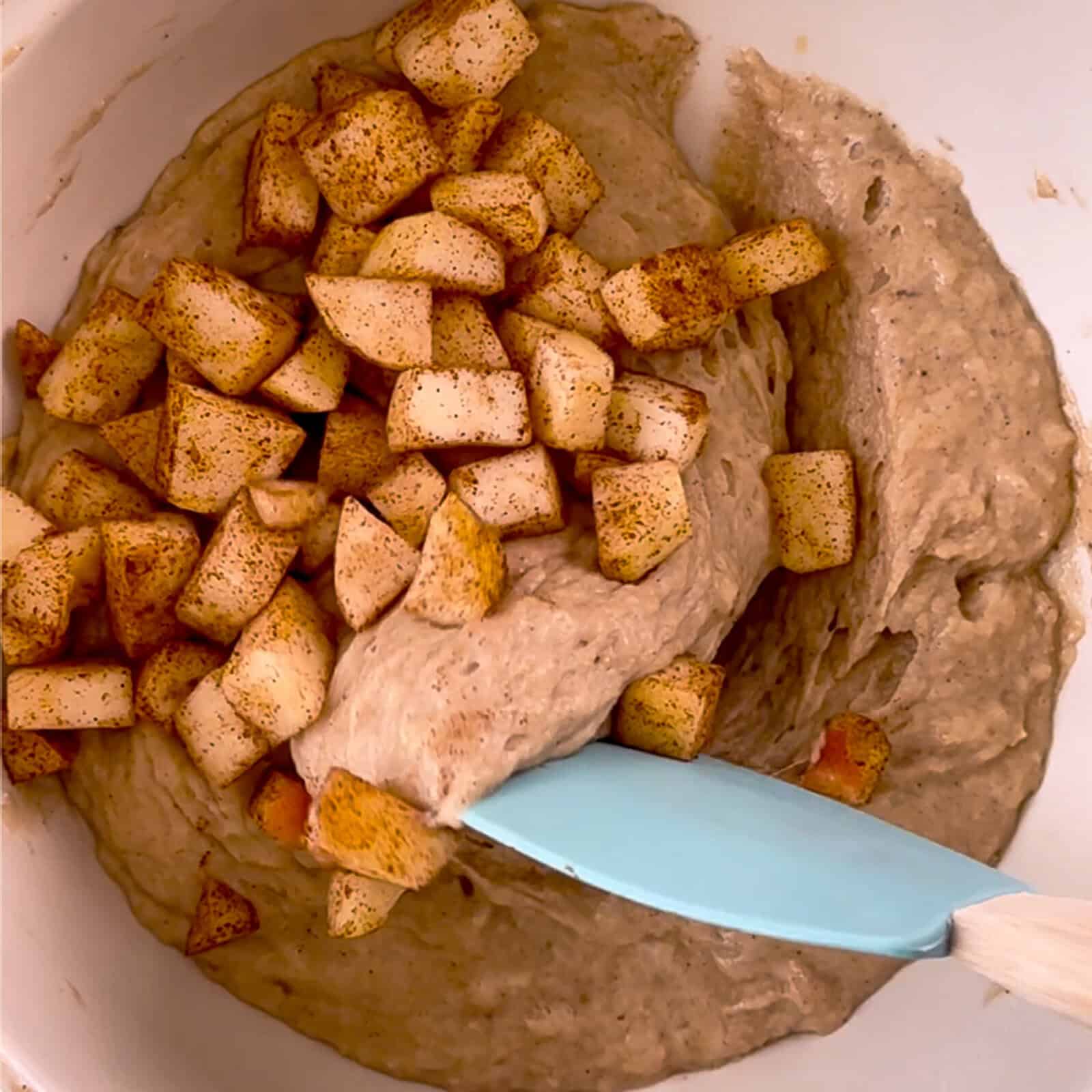 adding cinnamon coated apple chunks into banana bread batter