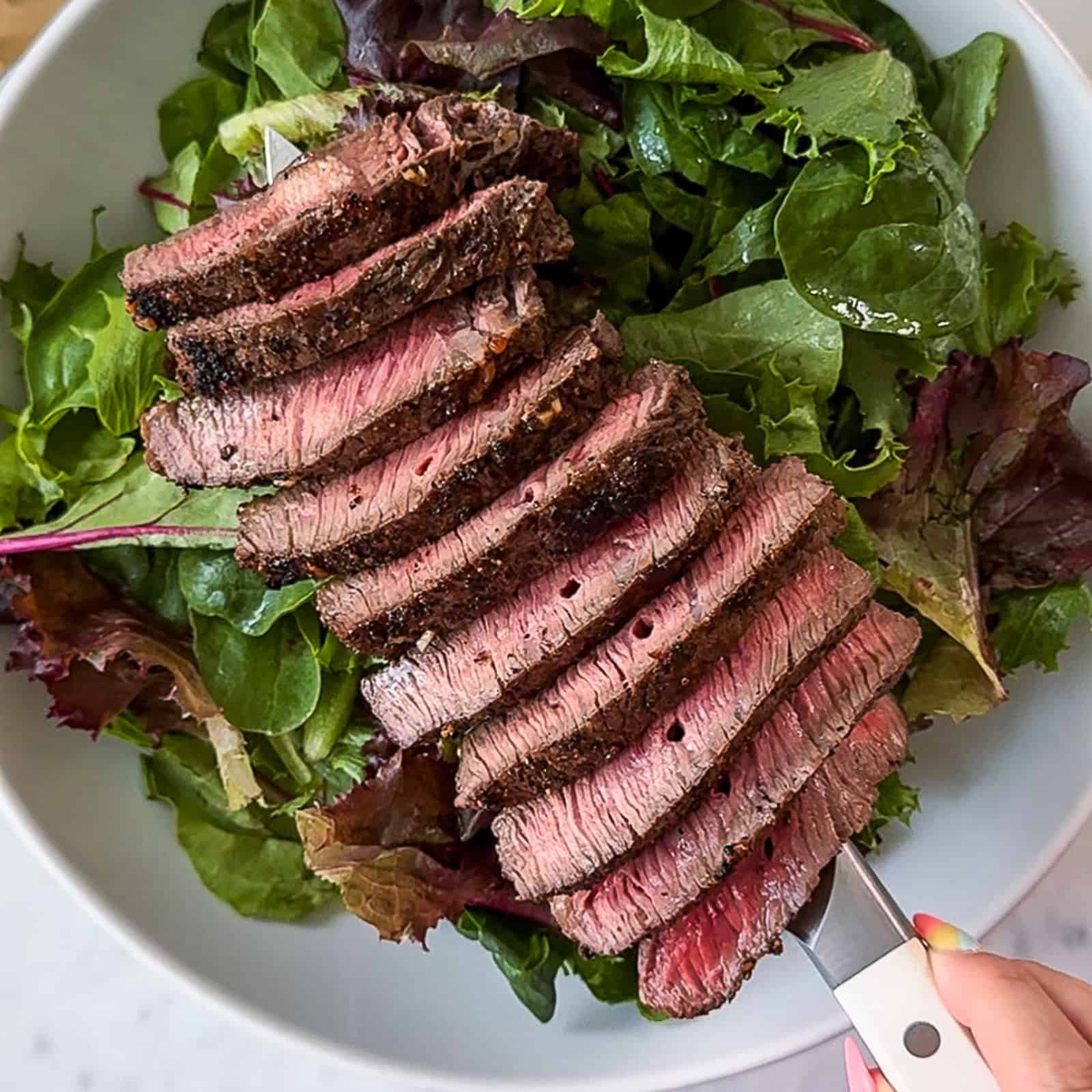 Drizzling balsamic dressing over a steak and mango salad